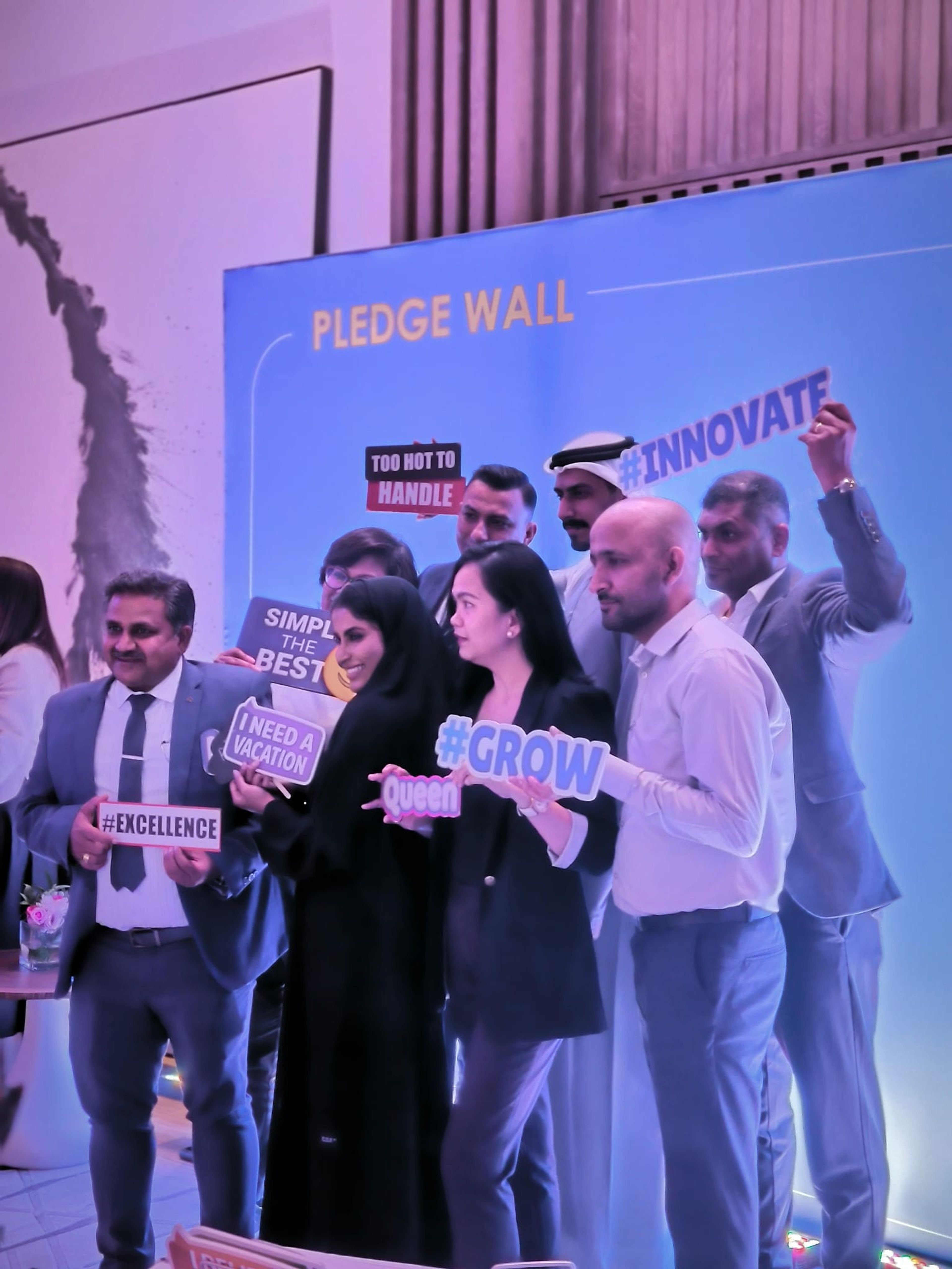 Conference guests holding Inspire, Innovate and Grow signs at the pledge wall