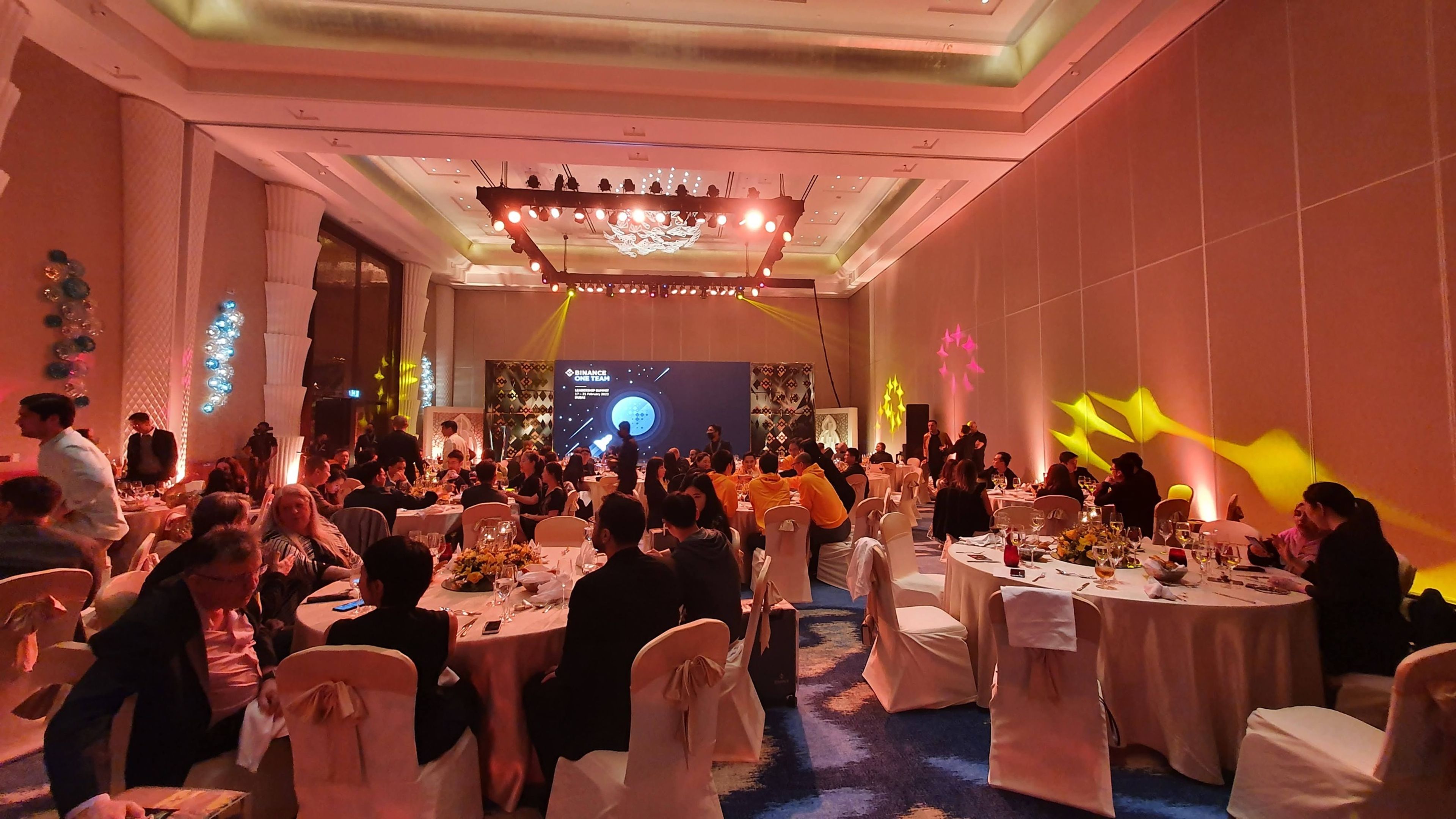 An elegantly decorated venue for a corporate gala dinner, featuring ambient lighting, floral centerpieces, and a grand chandelier