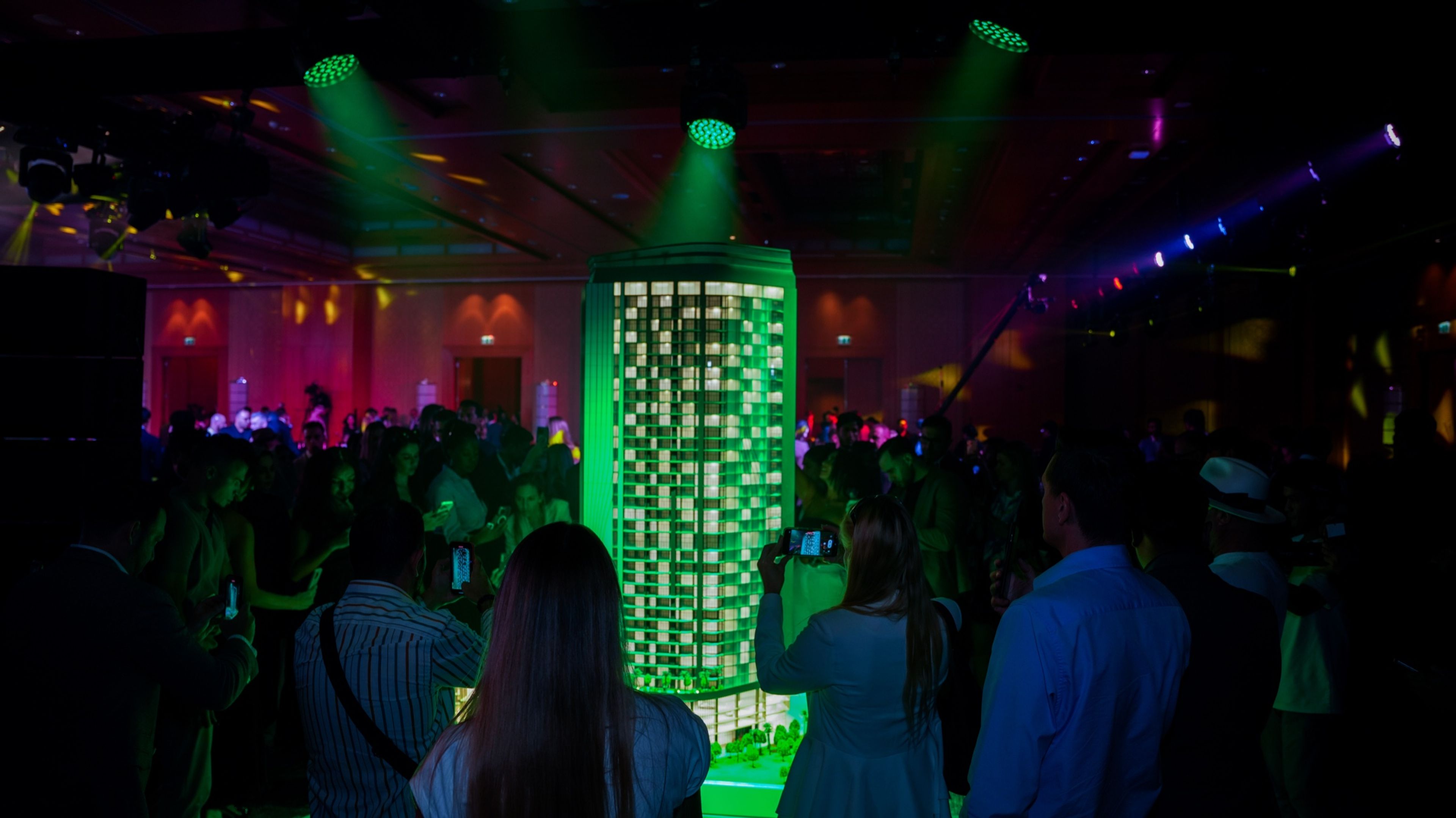 Guests around an illuminated green installation at a nightclub-style event