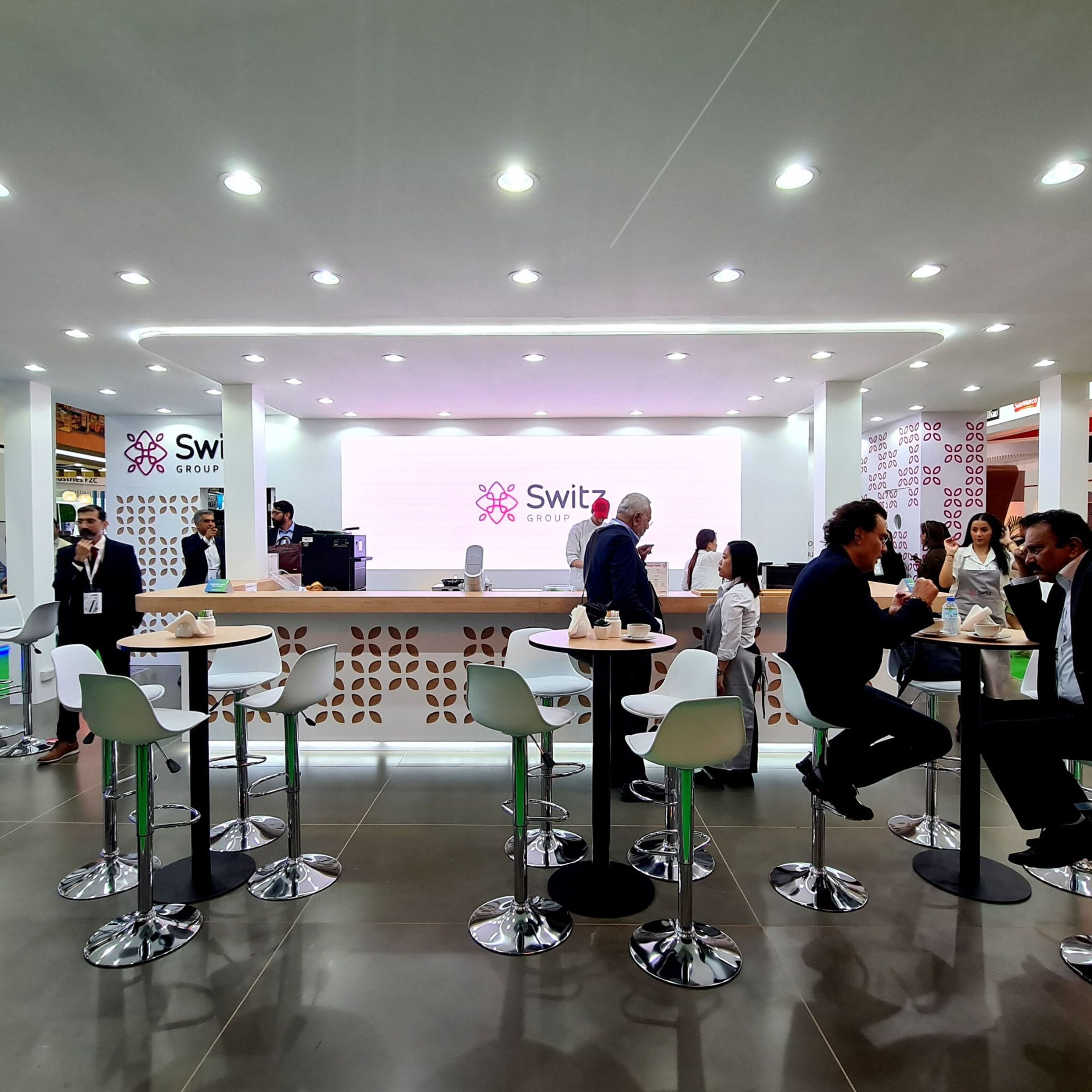 Switz Group stand upper-deck meeting lounge with high tables and branded bar