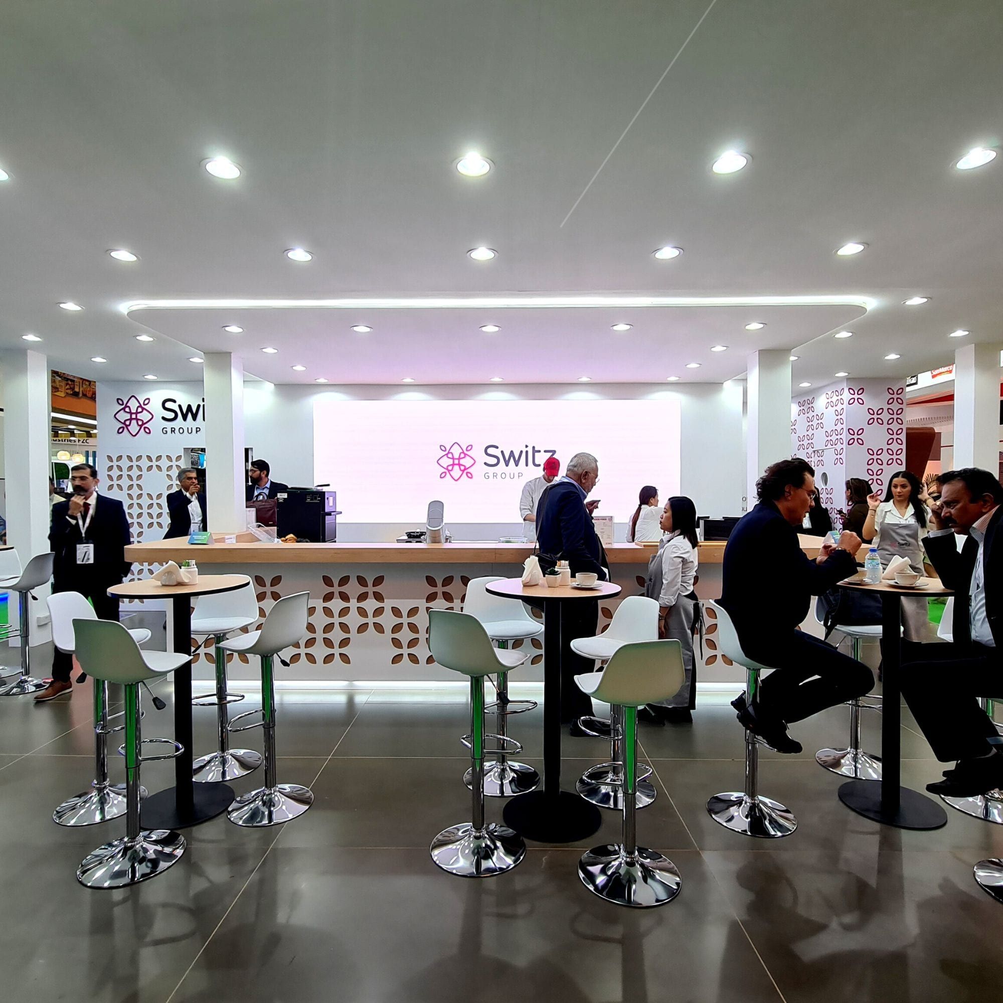 Switz Group stand upper-deck meeting lounge with high tables and branded bar
