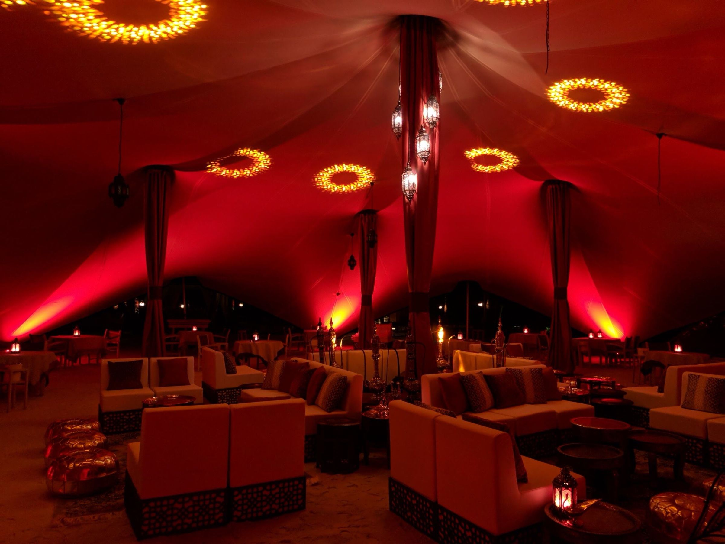 Arabian-style tent interior with red lighting and majlis seating