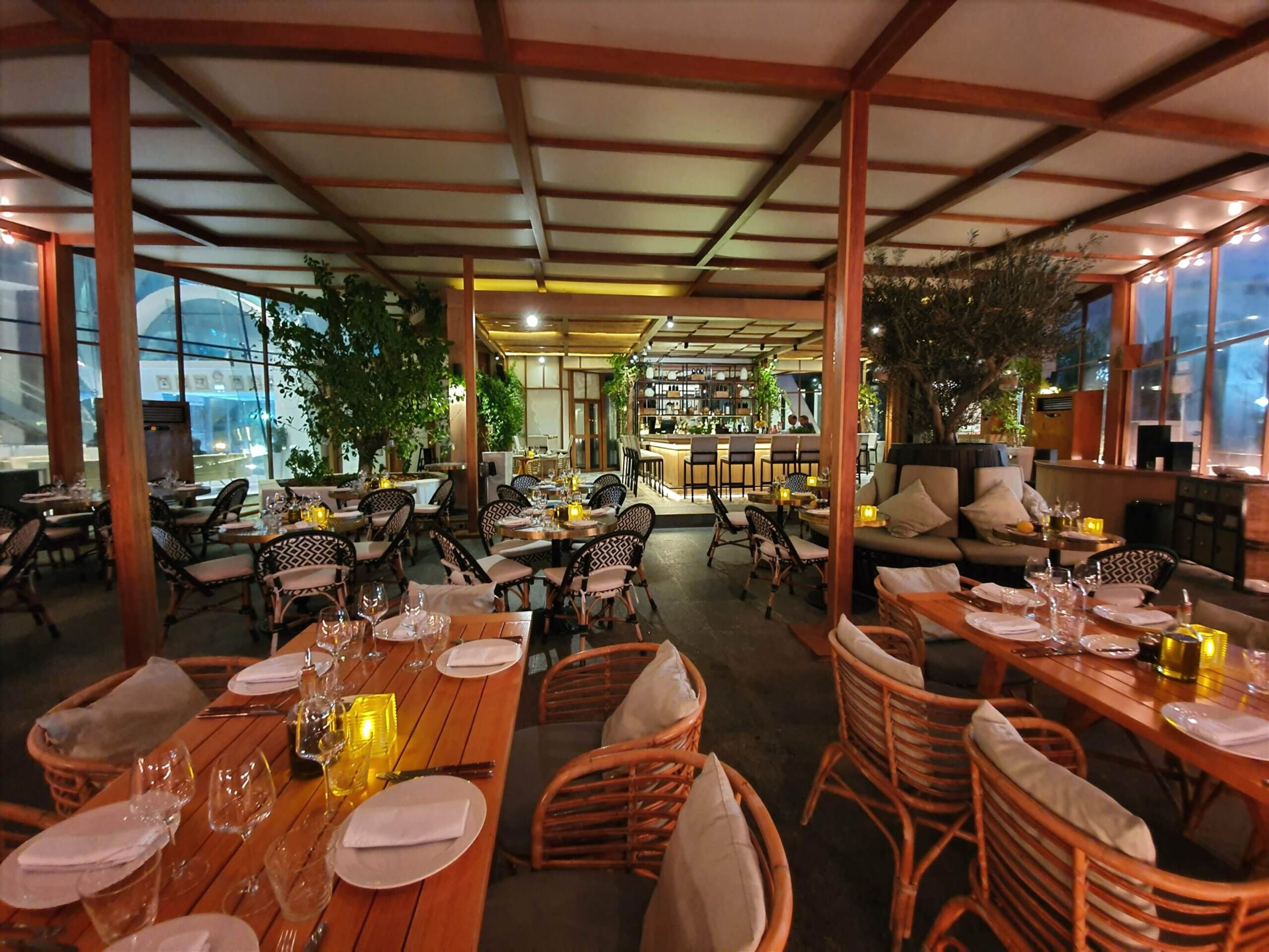 Evening terrace dinner setup with wooden tables and warm lighting