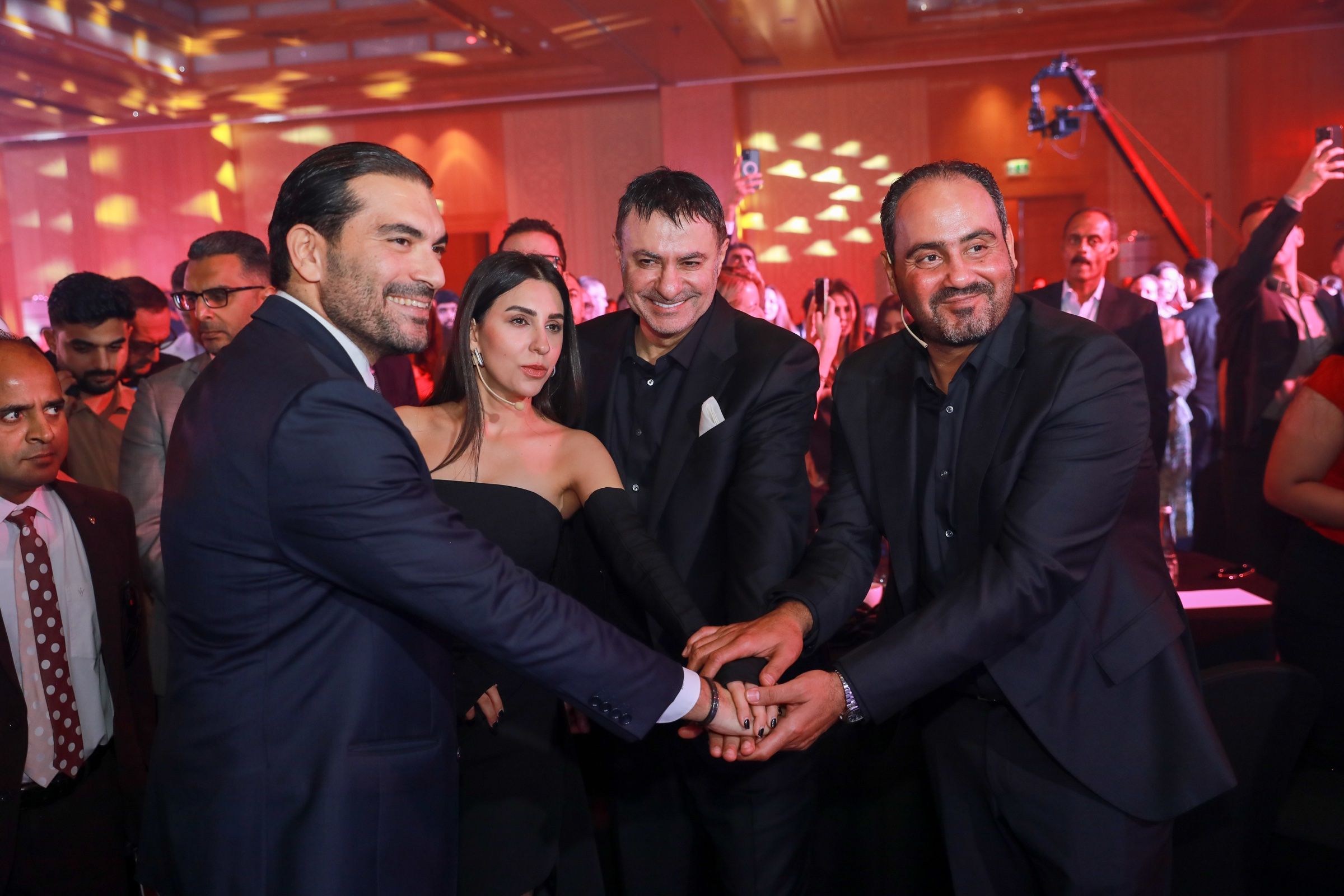 Executives shaking hands on stage at a corporate celebration
