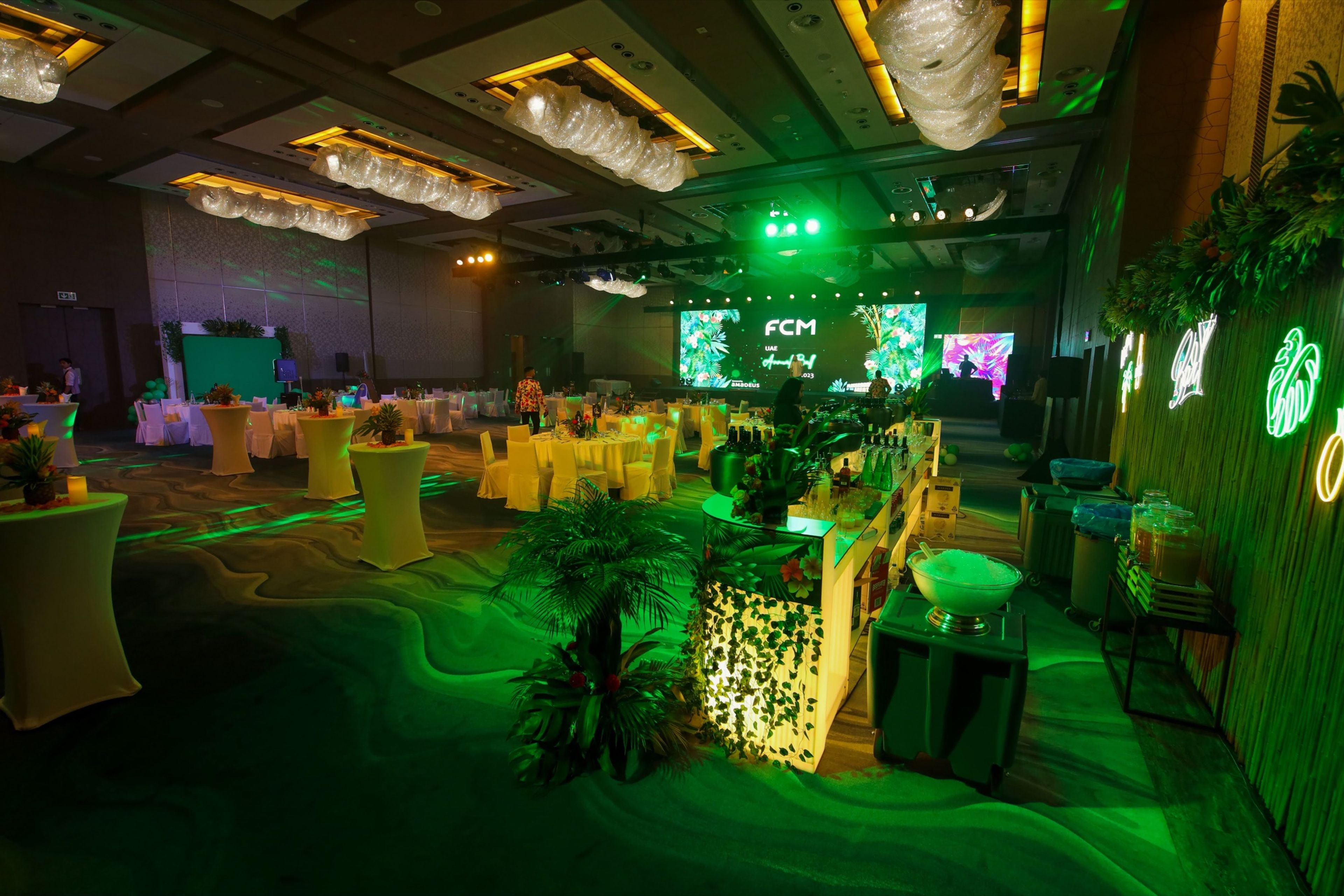Themed event space with green lighting and lush floral installations