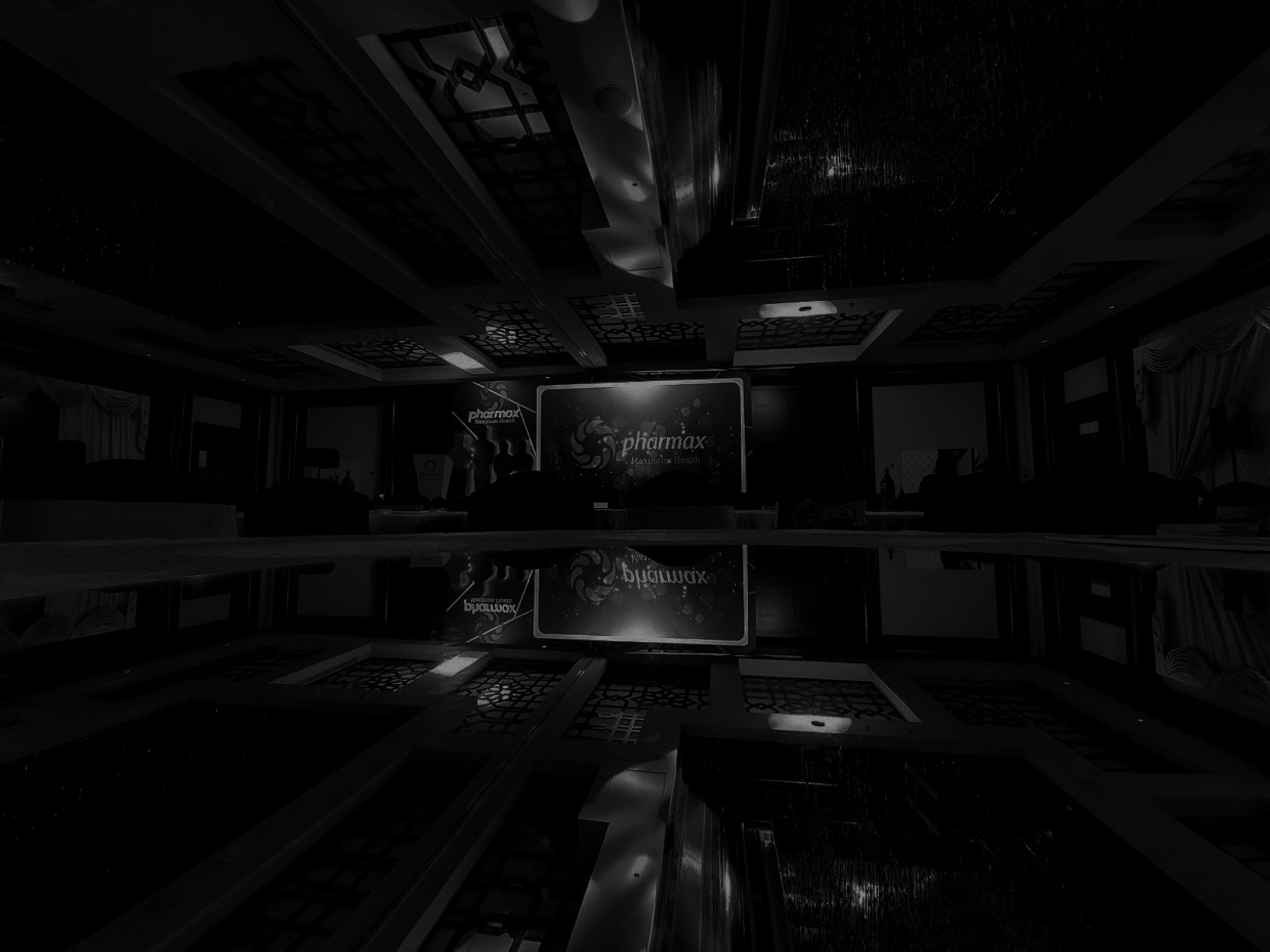 Dimly lit exhibition hall with a branded screen reflected in a glossy floor