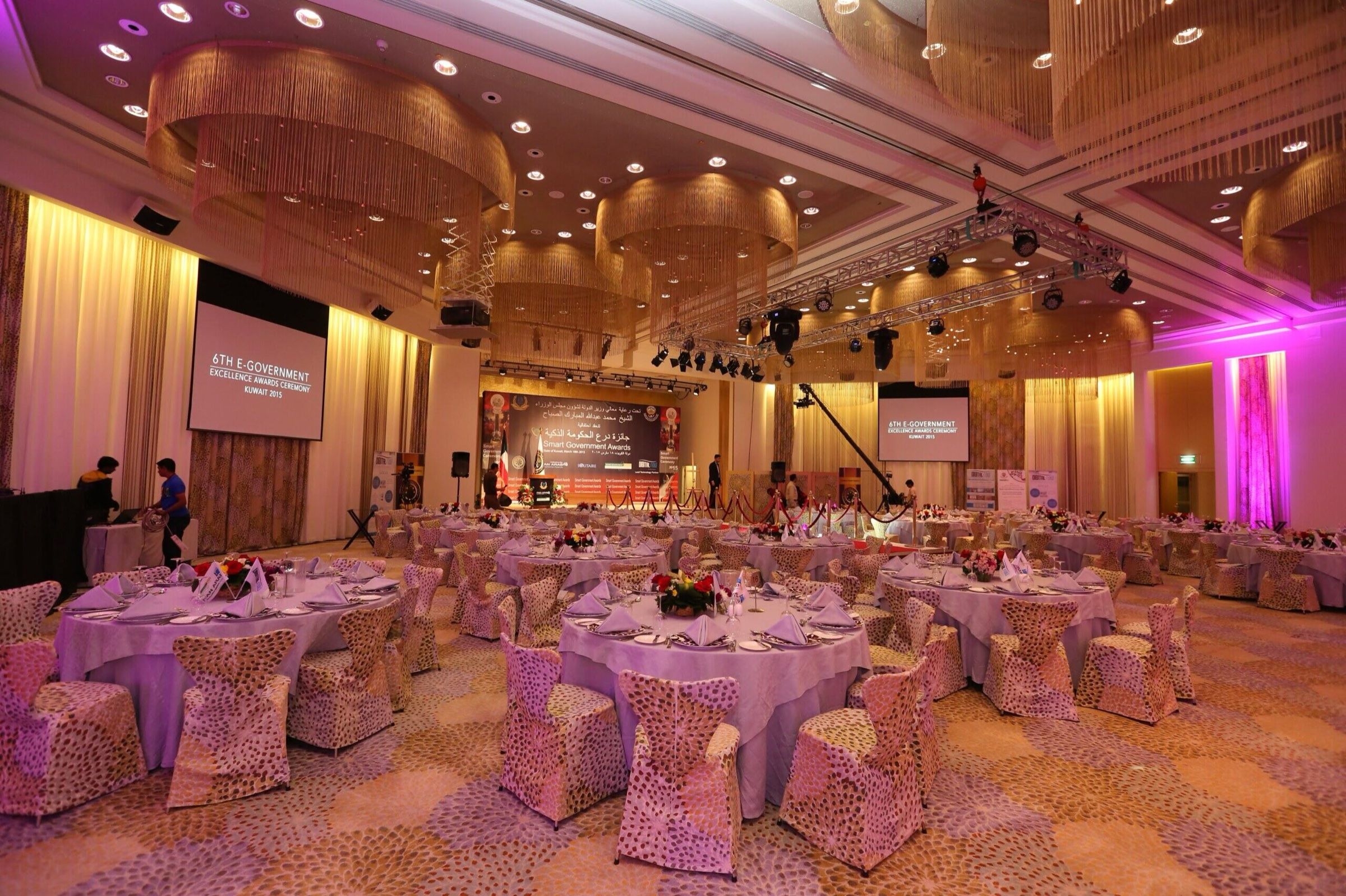 Gala dinner ballroom with pink uplighting and decorated round tables
