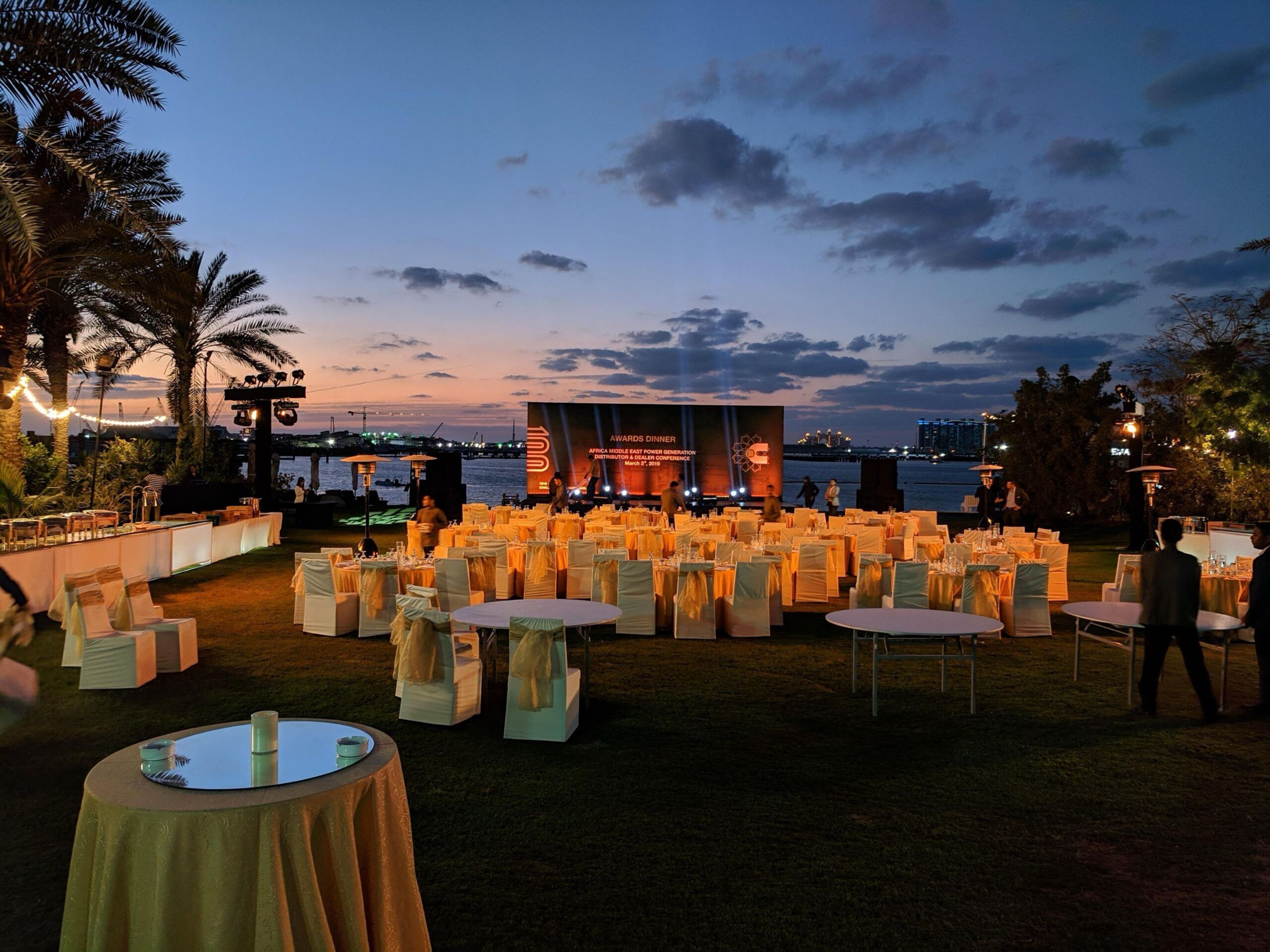 Beachside evening event with a stage and lounge seating at sunset