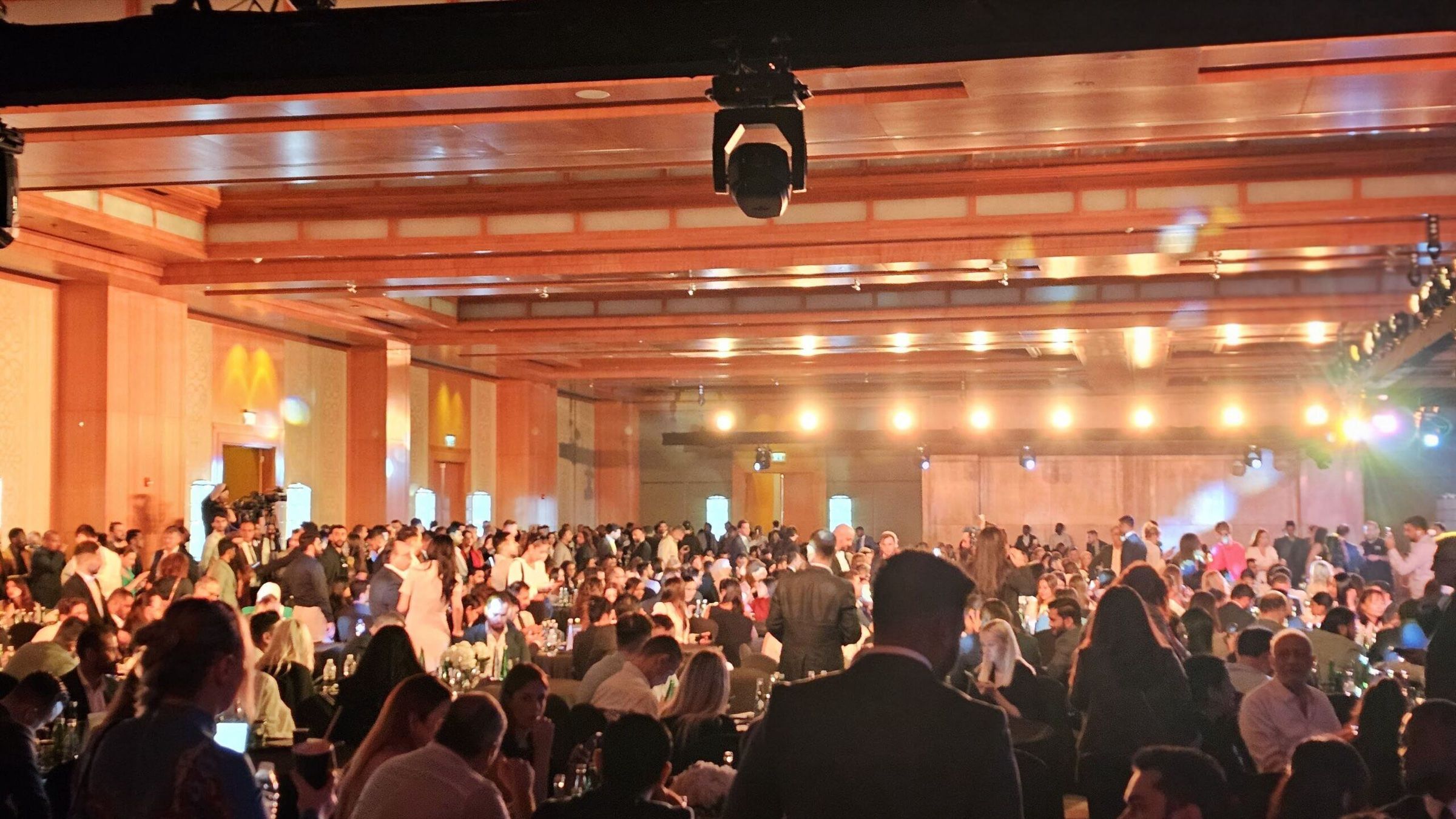 Packed auditorium audience at a corporate conference with stage lighting