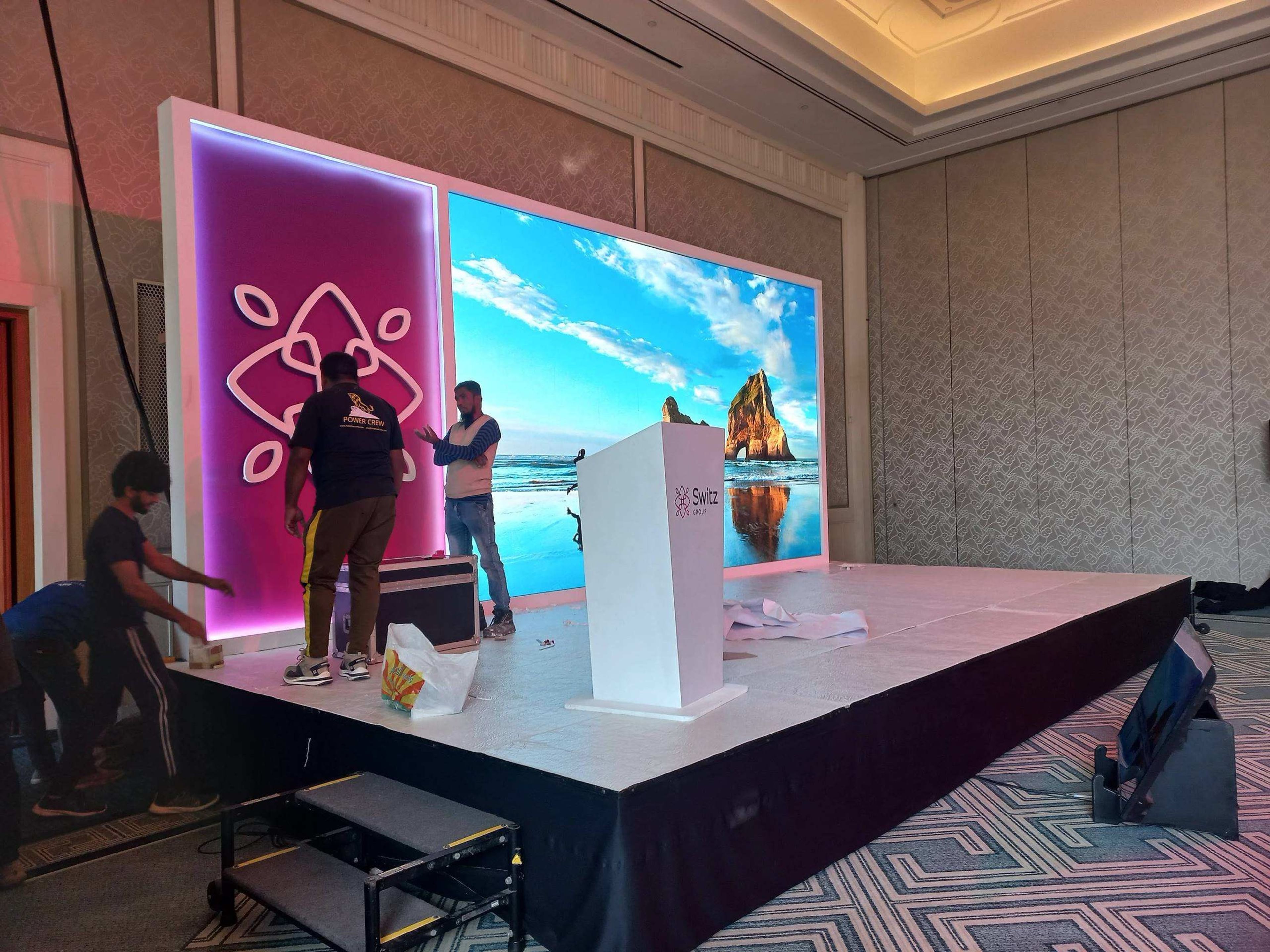 Presenters on a stage with a colourful LED screen at a corporate launch