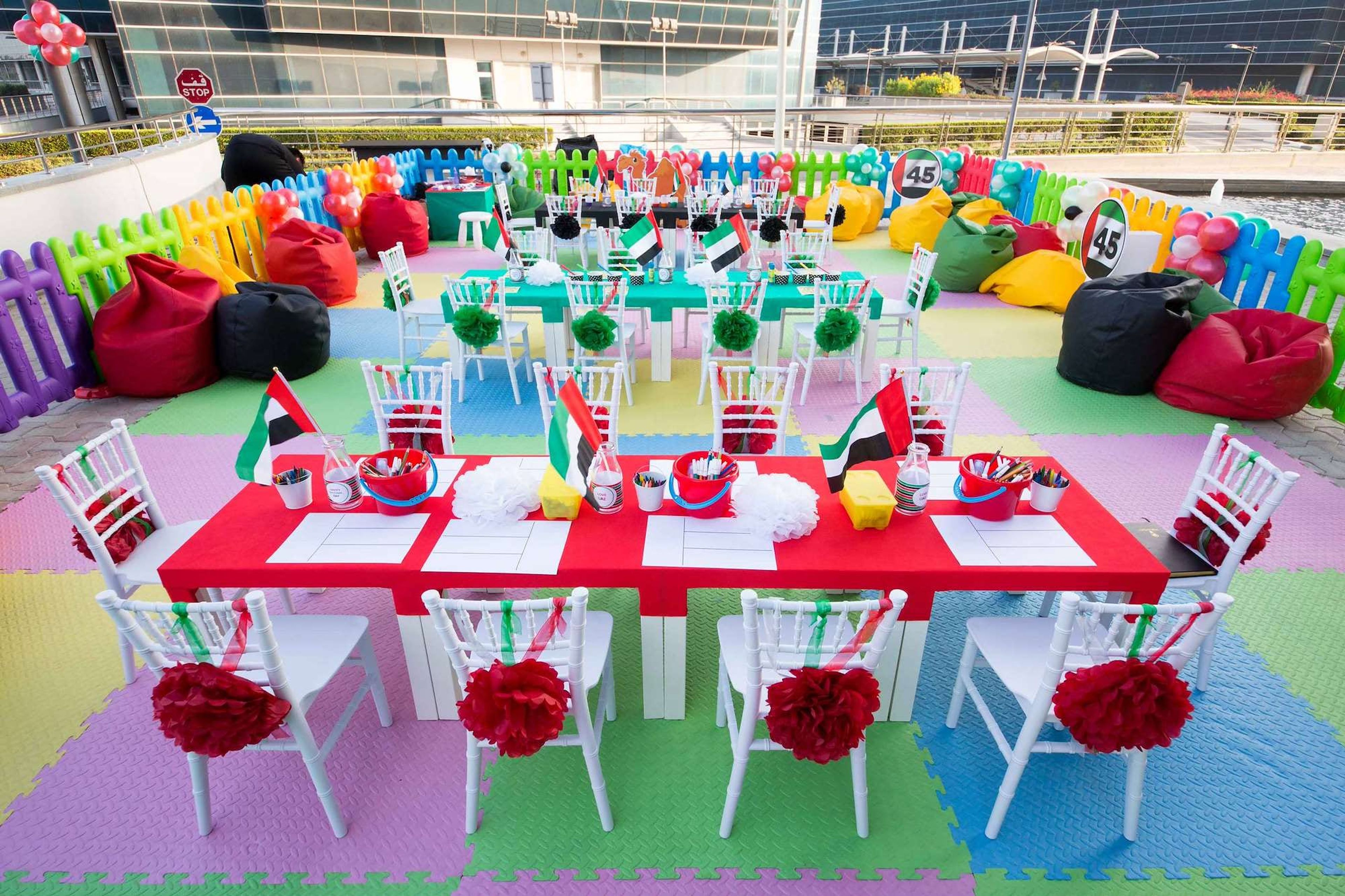 Kids' activity tables in red, green and white with UAE flags and colourful seating
