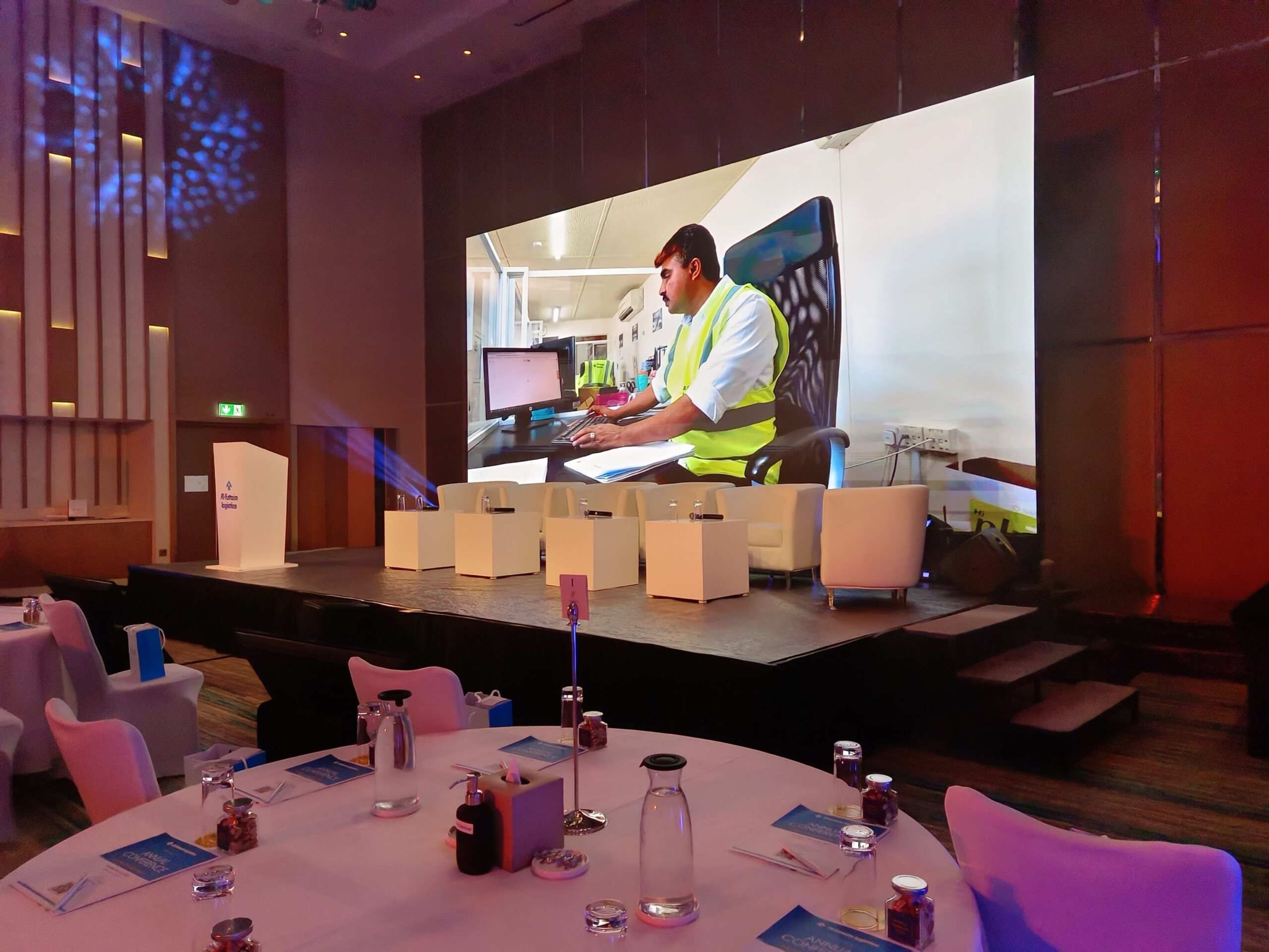 Presenter on stage with an LED screen at a corporate dinner event