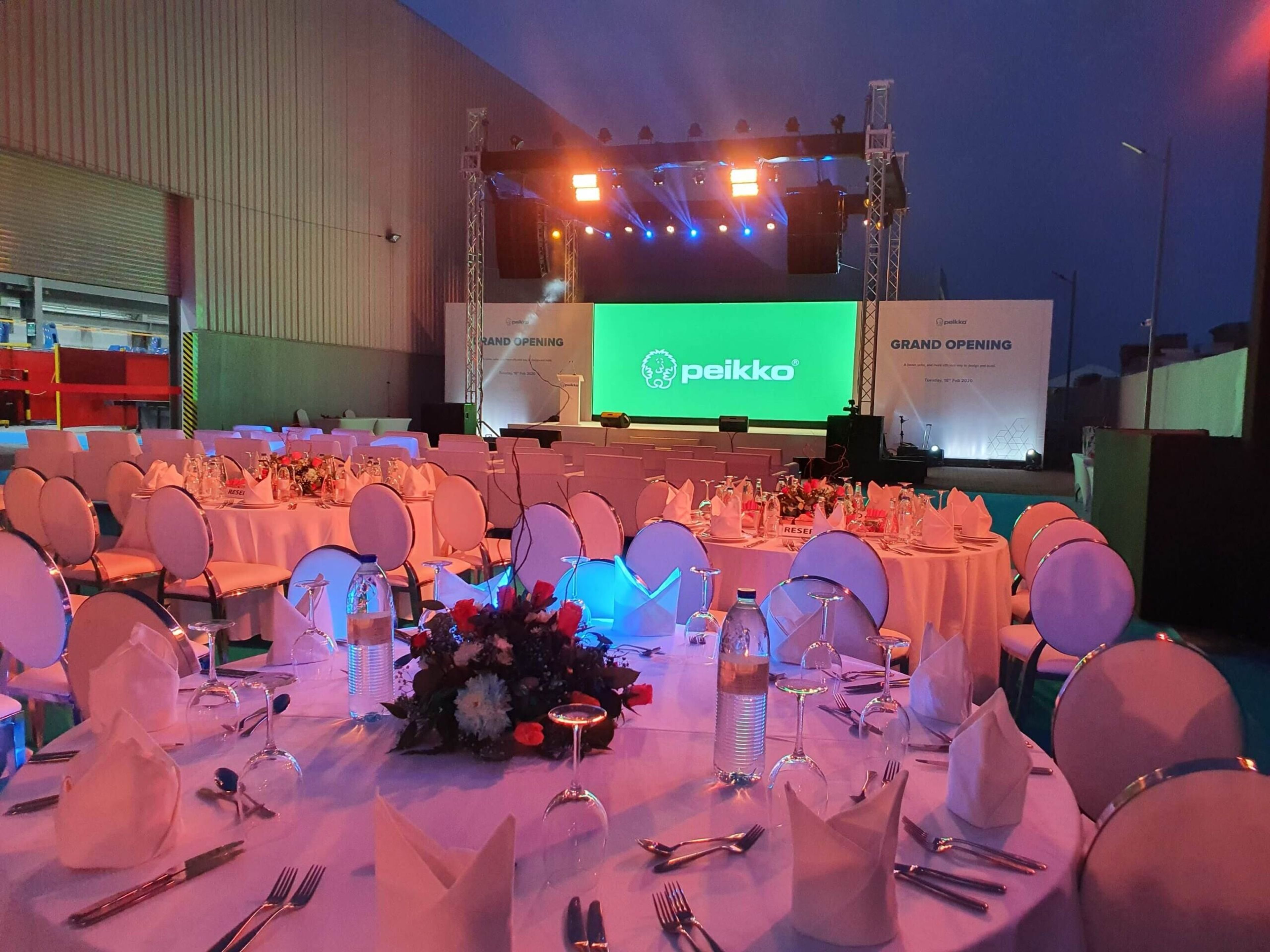 Conference ballroom with a green LED stage screen and draped chairs