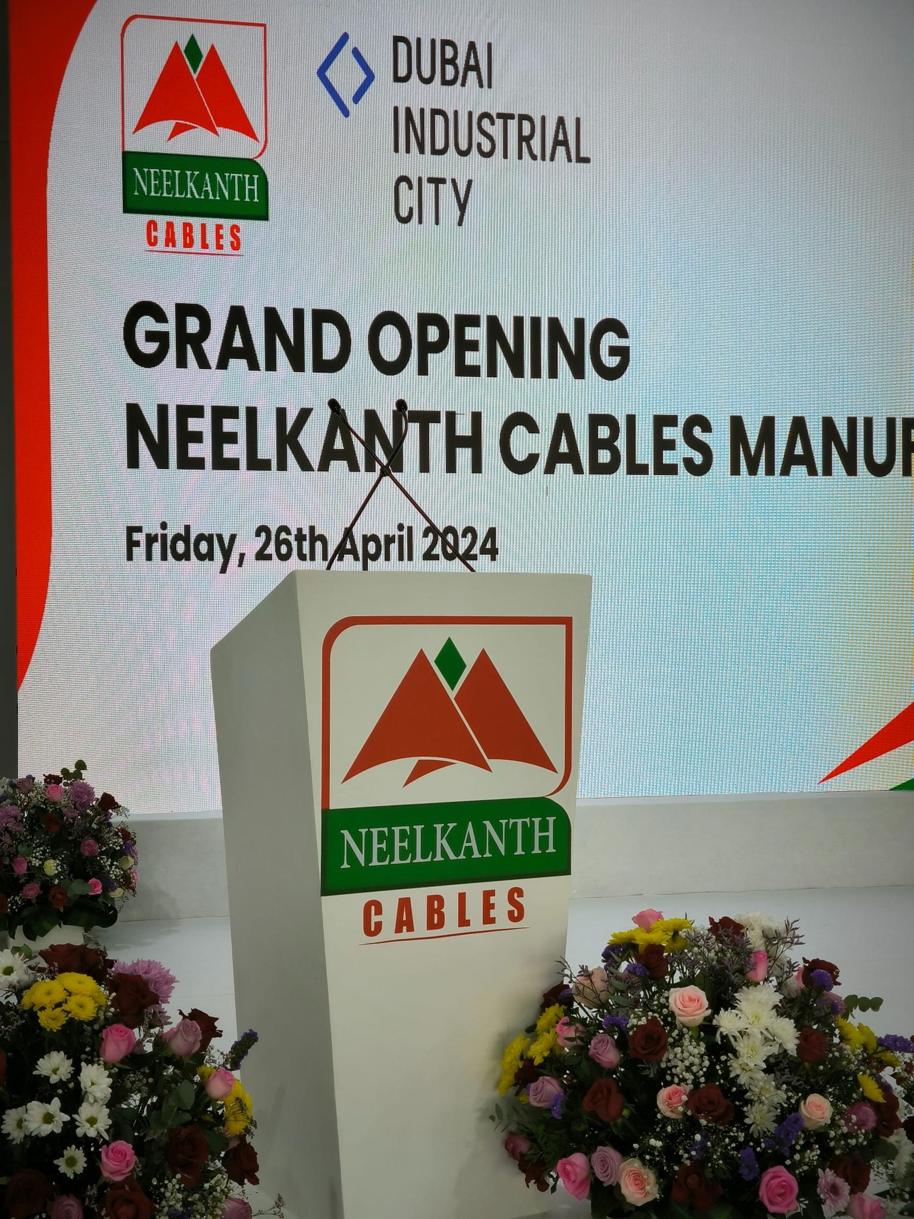 Neelkanth Cables branded lectern and floral display on stage
