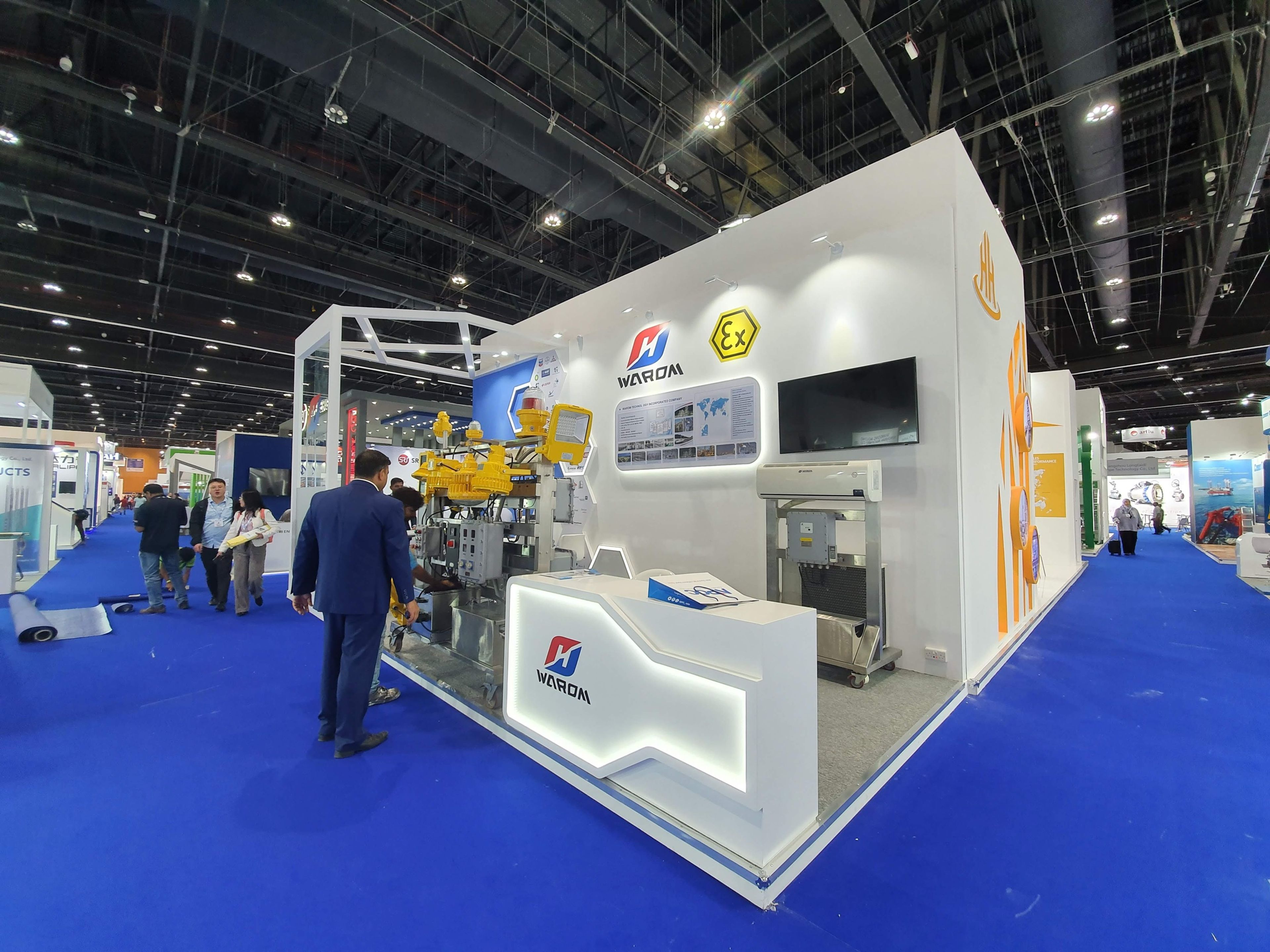 Custom white exhibition stand with an illuminated reception counter, screen and product displays at a Dubai trade show