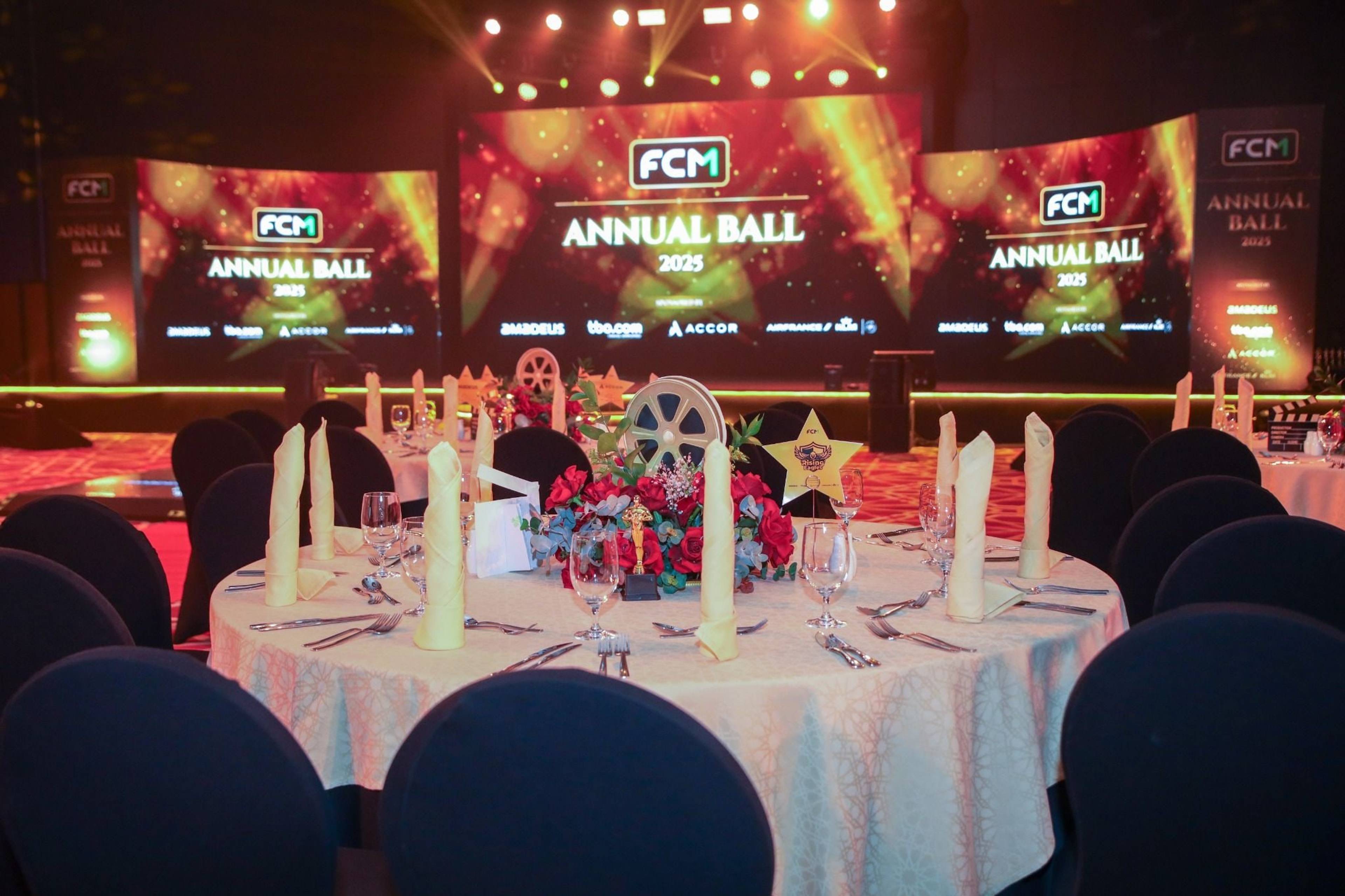 Gala dinner table with floral centrepiece facing the three-screen stage at the FCM Annual Ball 2025