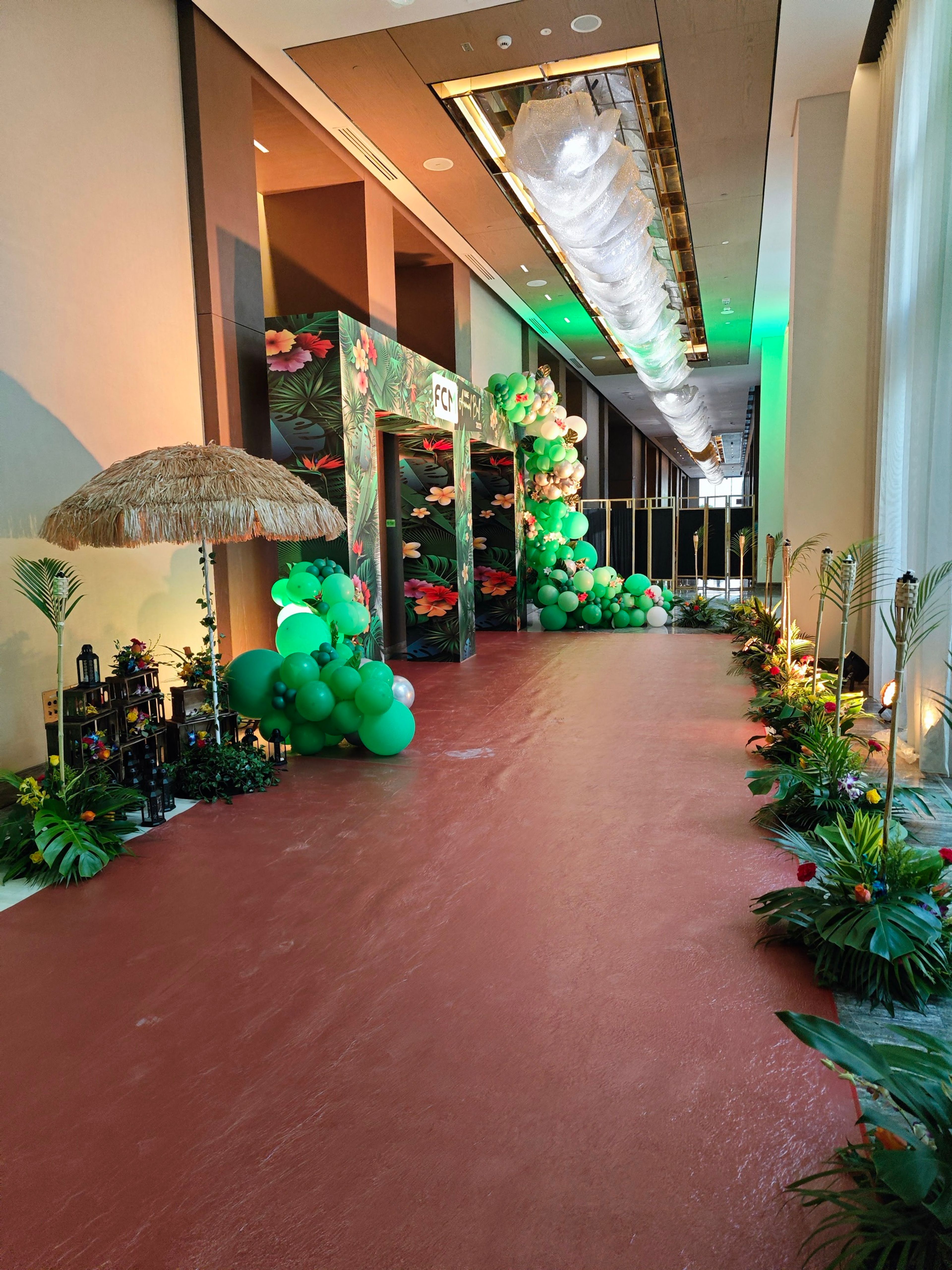 Entrance walkway lined with green balloon and floral installations