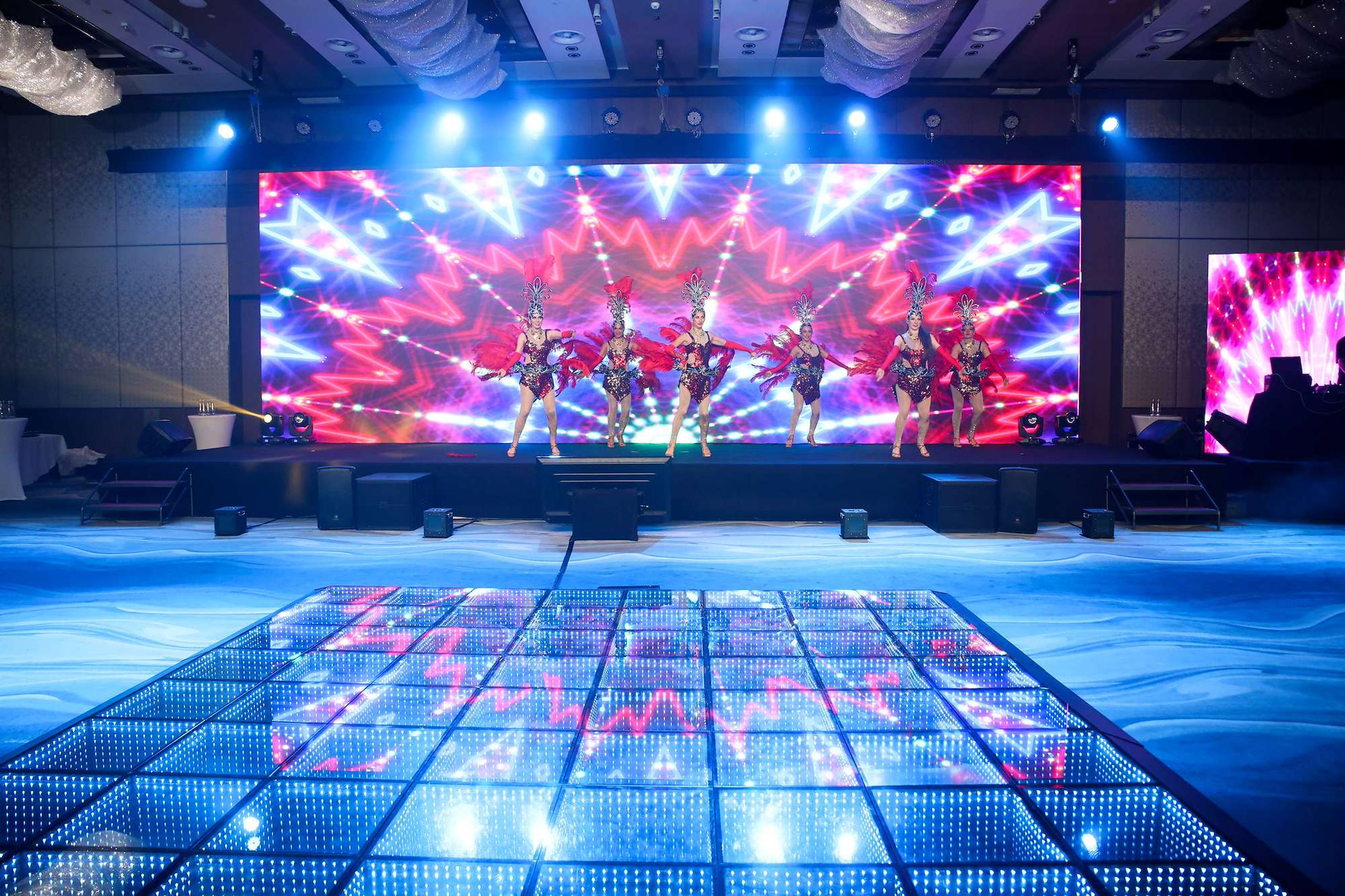 Hotel ballroom set for a corporate gala dinner with a stage, LED wall, dancers and an LED dance floor