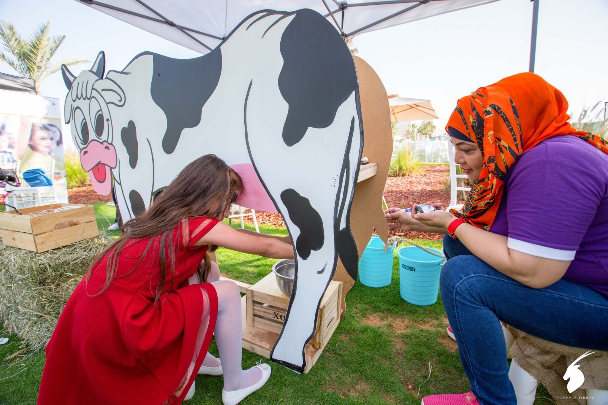 Children trying a cow milking game at the farm-themed family day