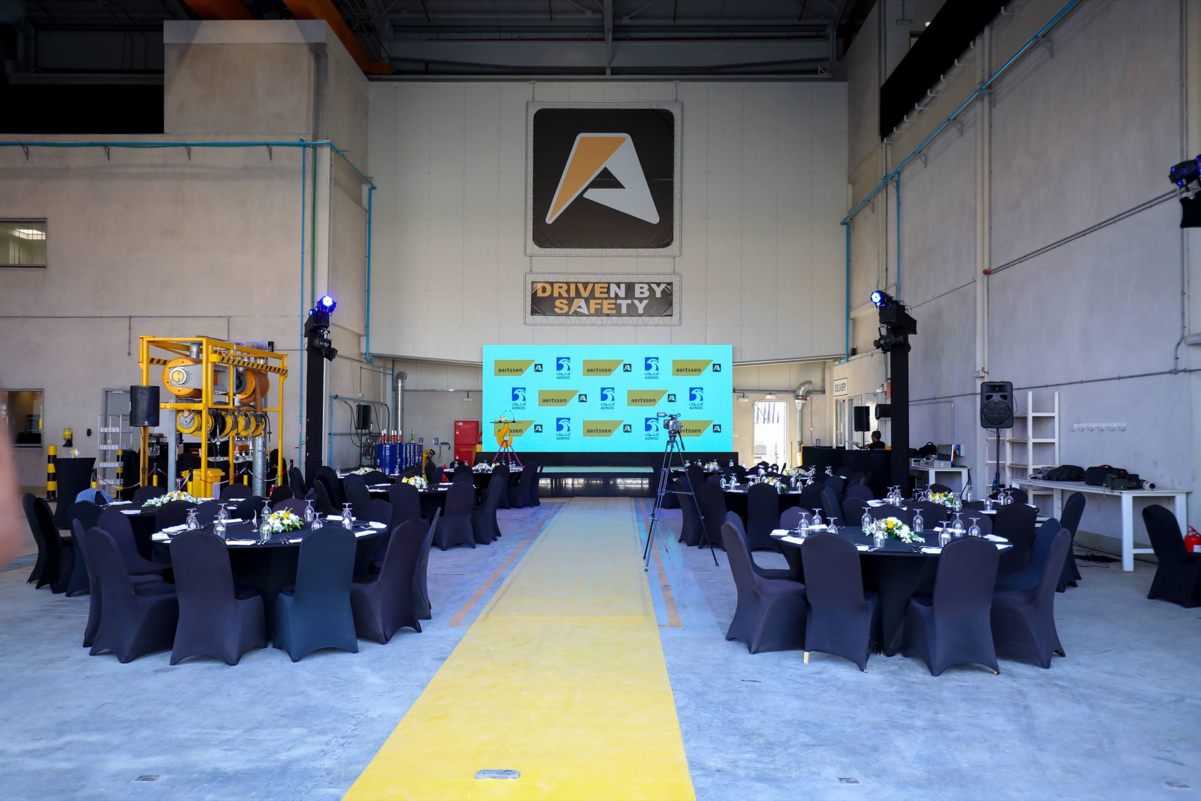 Industrial hall set with round tables and a stage for a facility launch