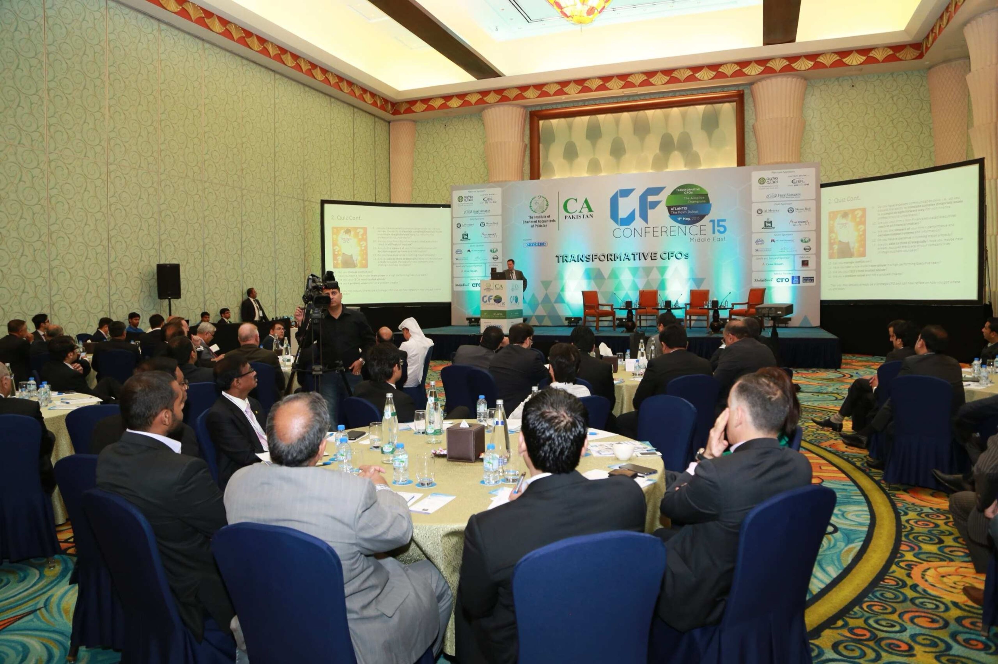 Delegates seated at round tables facing a branded conference stage