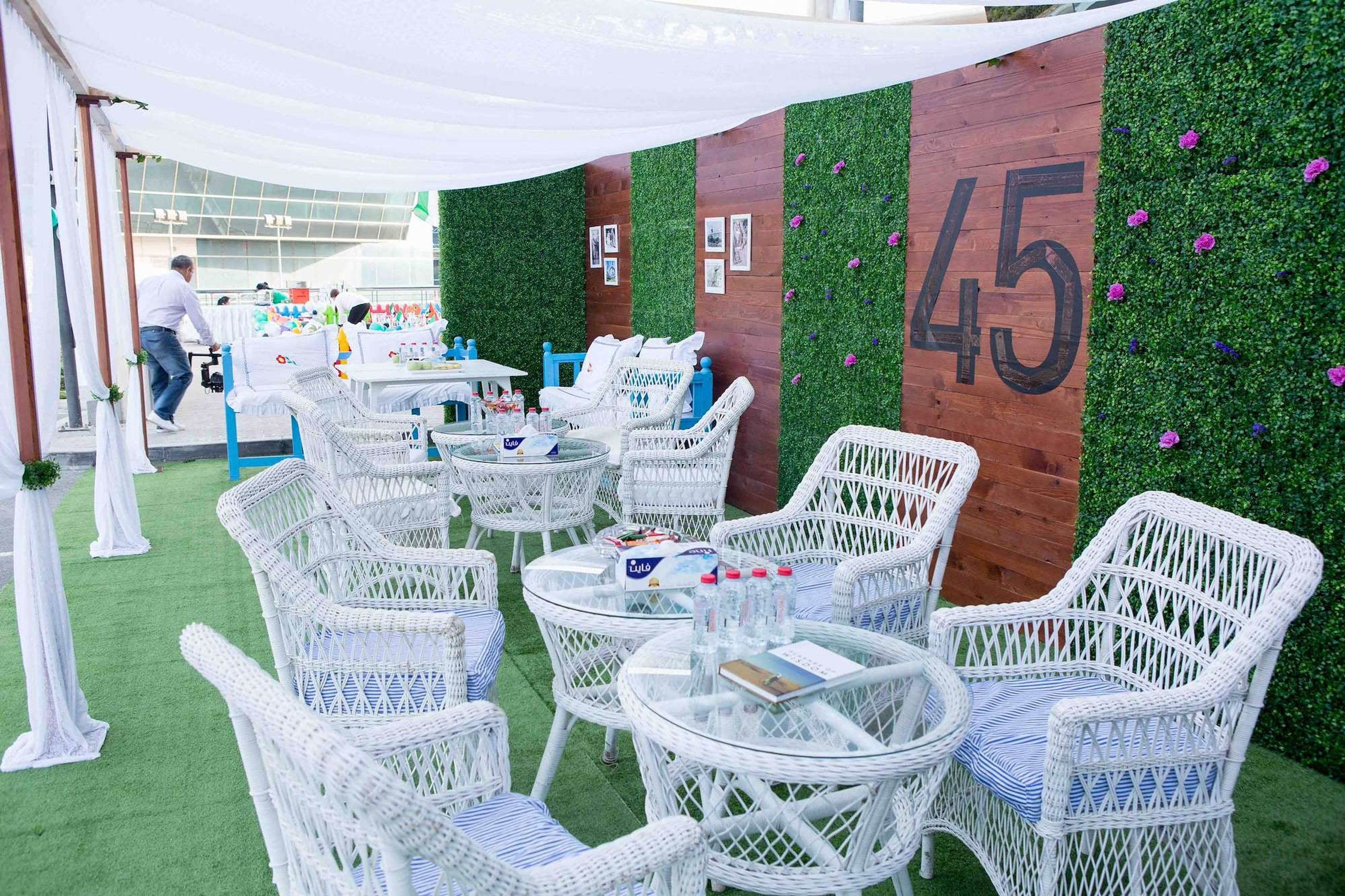 Garden lounge with white cane seating and a 45 sign marking the UAE's 45th National Day