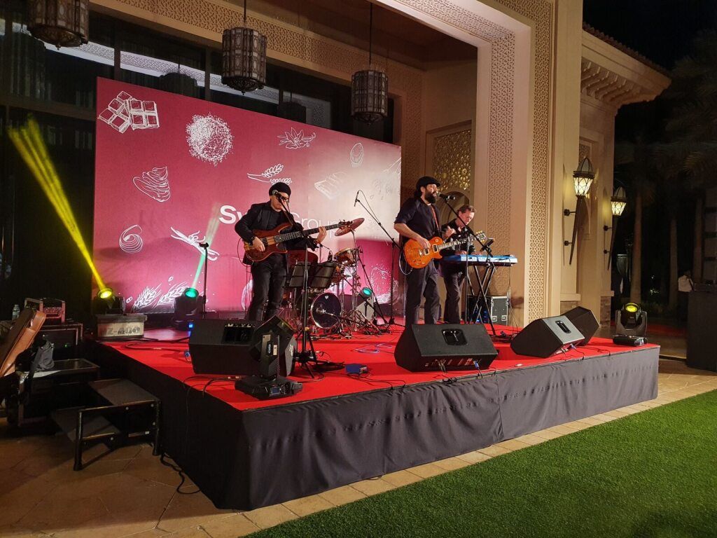 Live band performing on a red-lit stage at an evening event