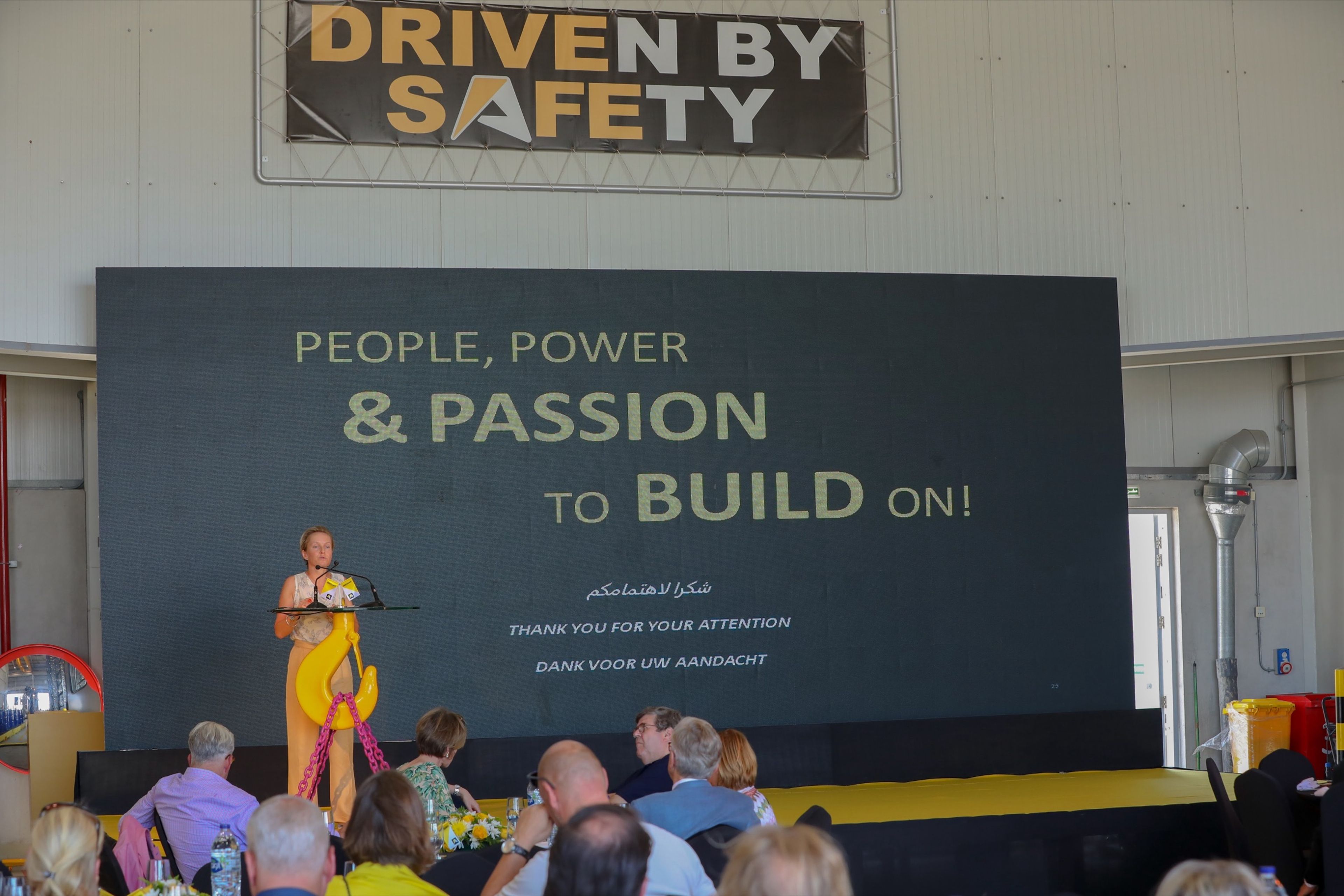 Speaker on stage in front of a People, Power and Passion brand screen