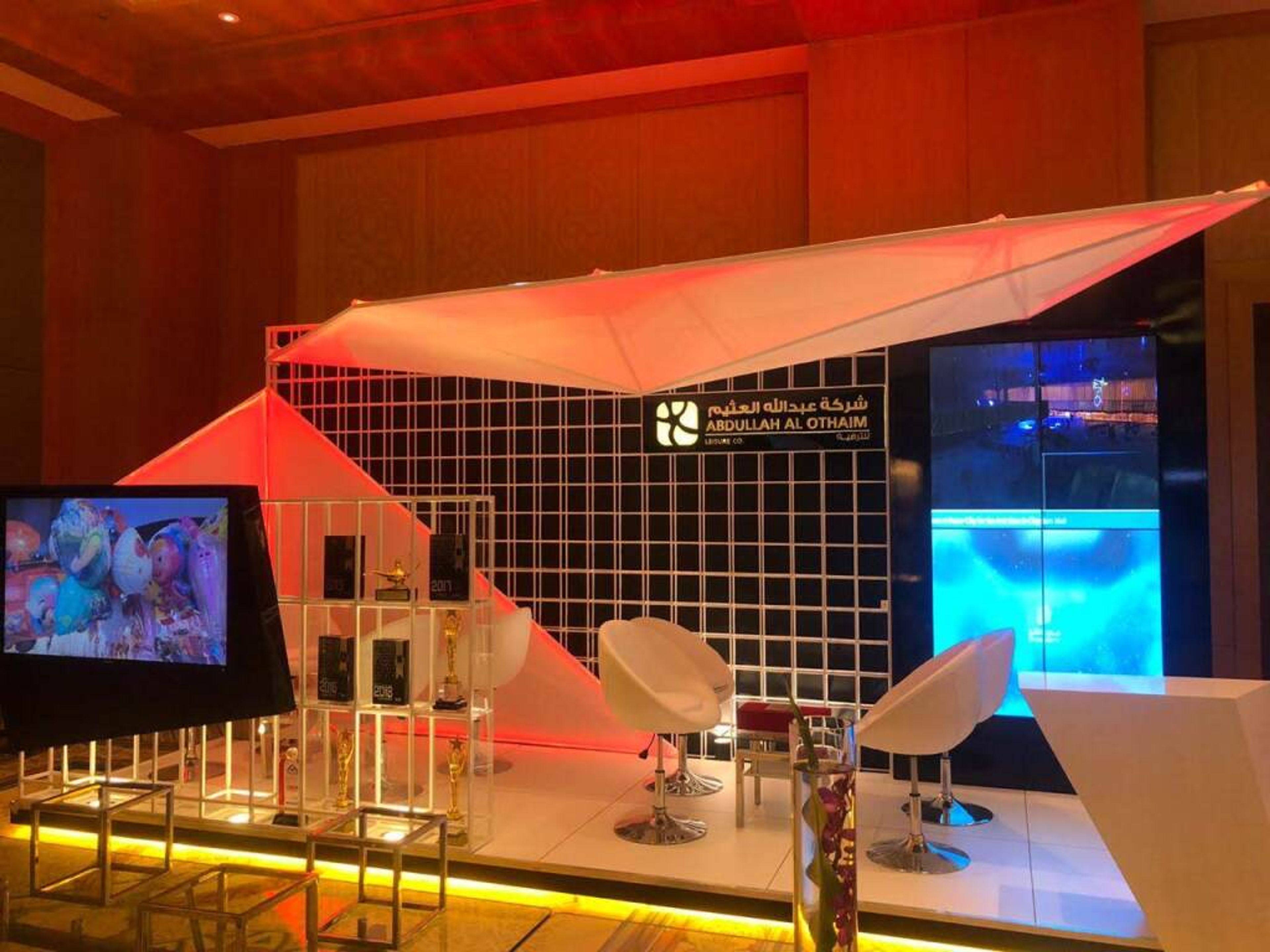 Modern exhibition stand with a lit canopy and lounge seating