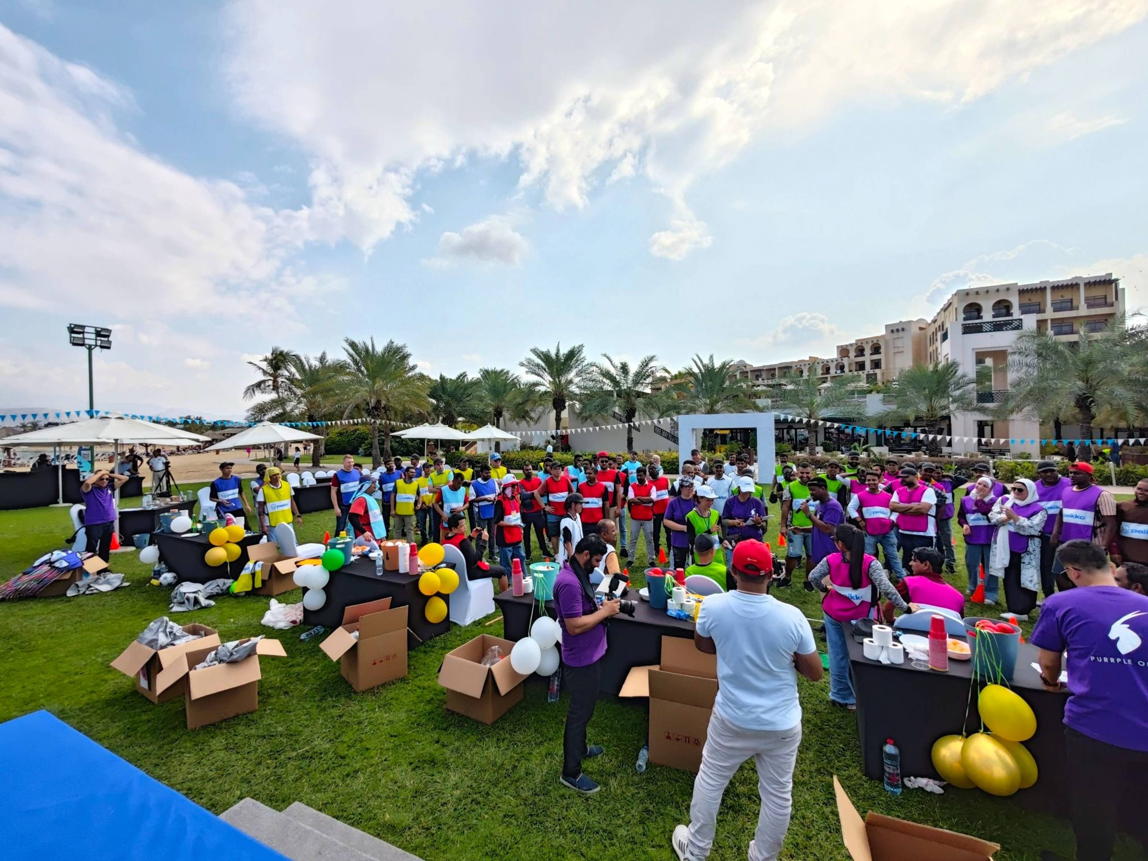 Peikko team building group in coloured team shirts on a seaside lawn at Hilton Ras Al Khaimah