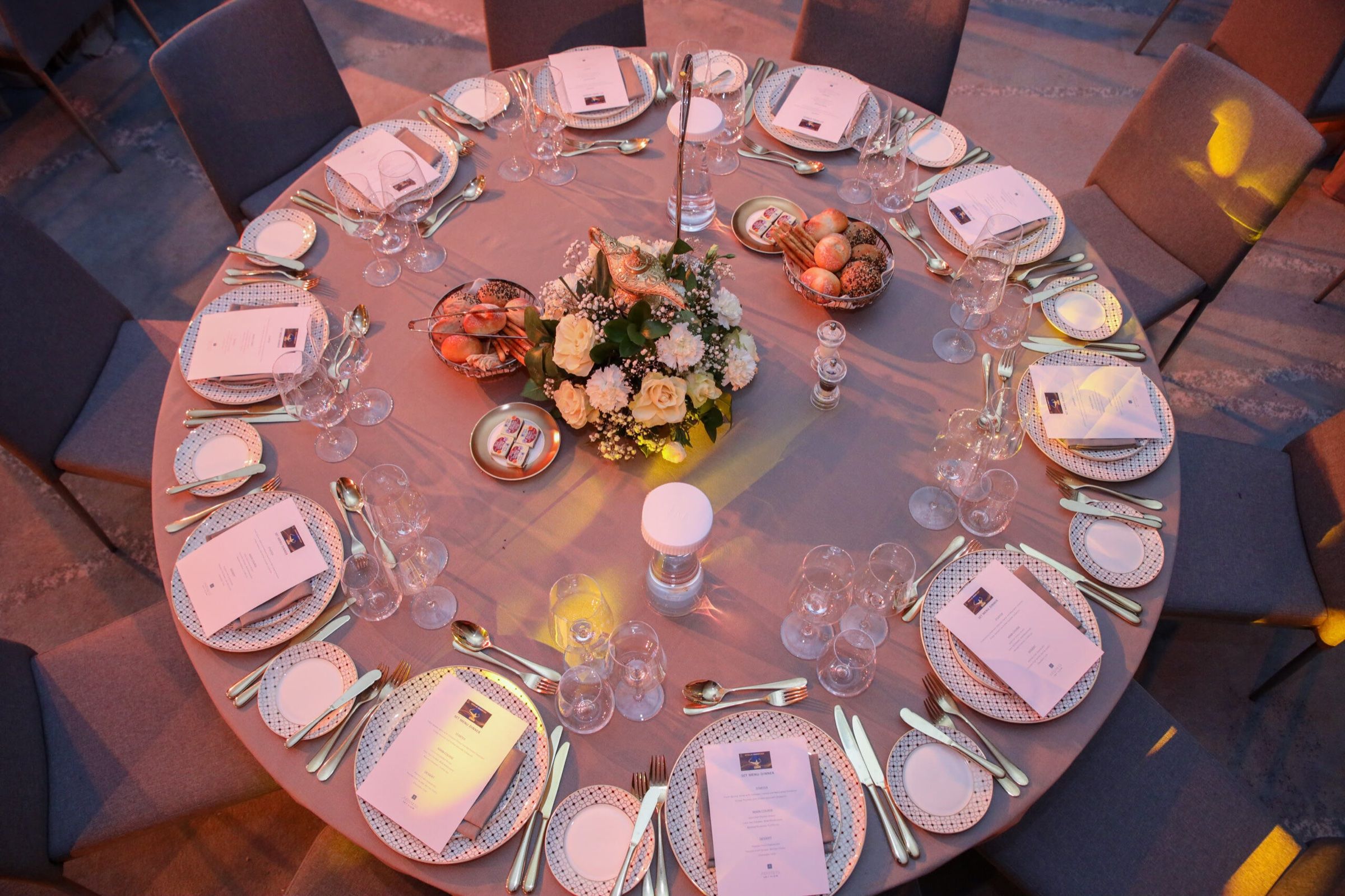 Elegant round dinner table with a floral centrepiece and fine tableware