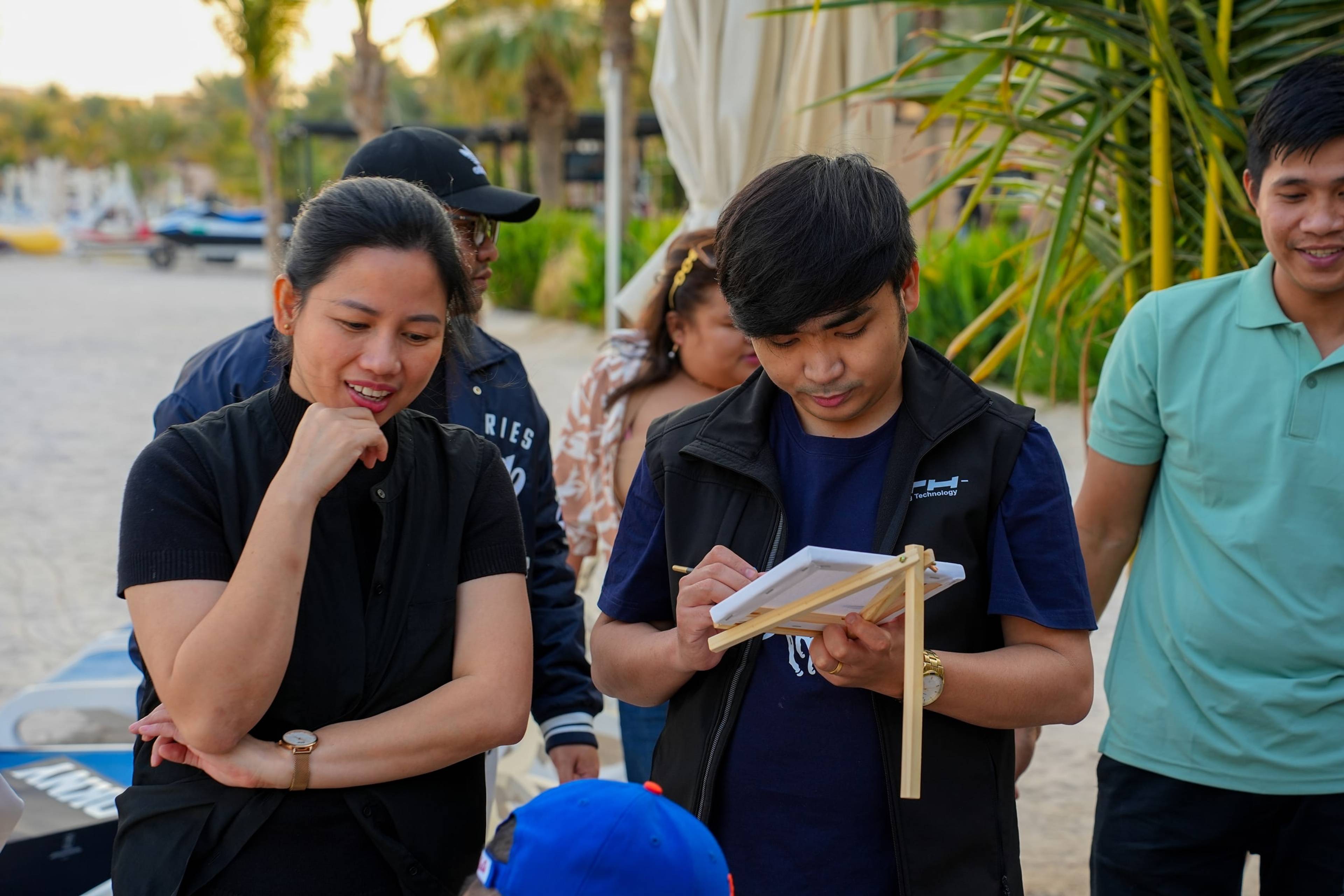 Team members sketching together during a beach team-building activity in Dubai