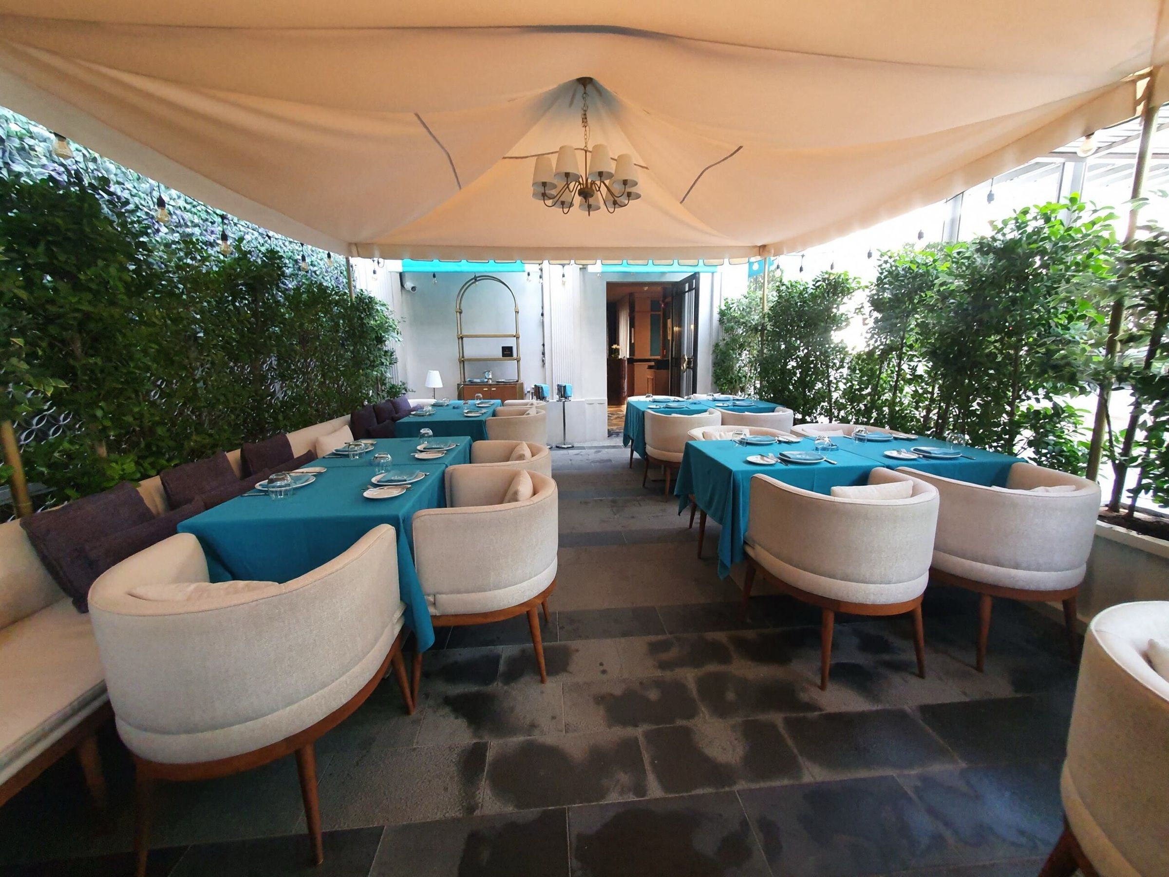 Outdoor dining area with teal-and-white seating under a canopy