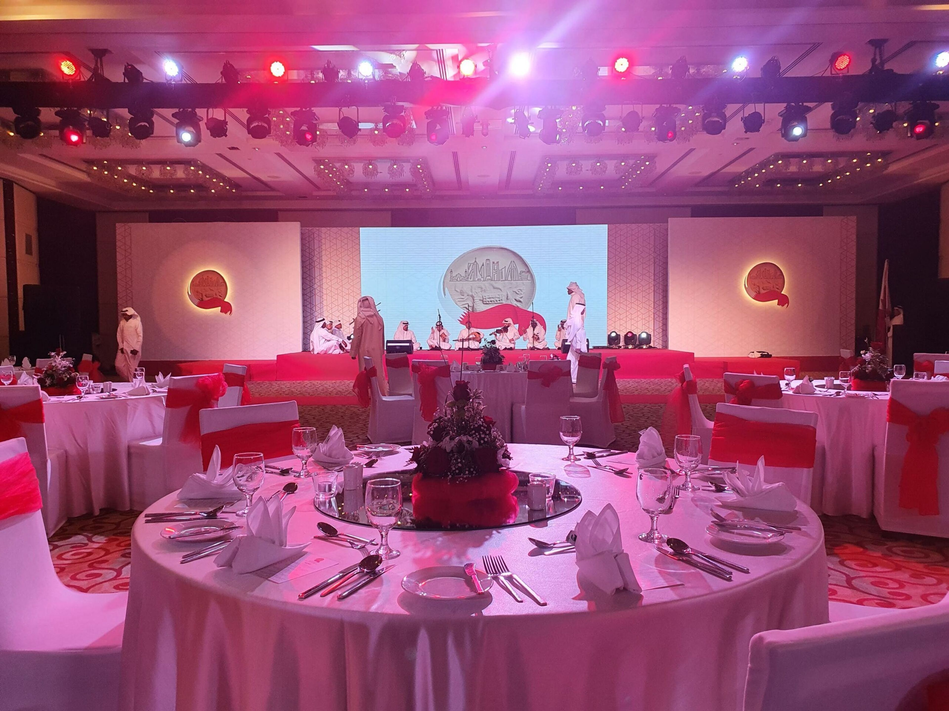 Gala dinner with round tables, pink décor and a stage screen