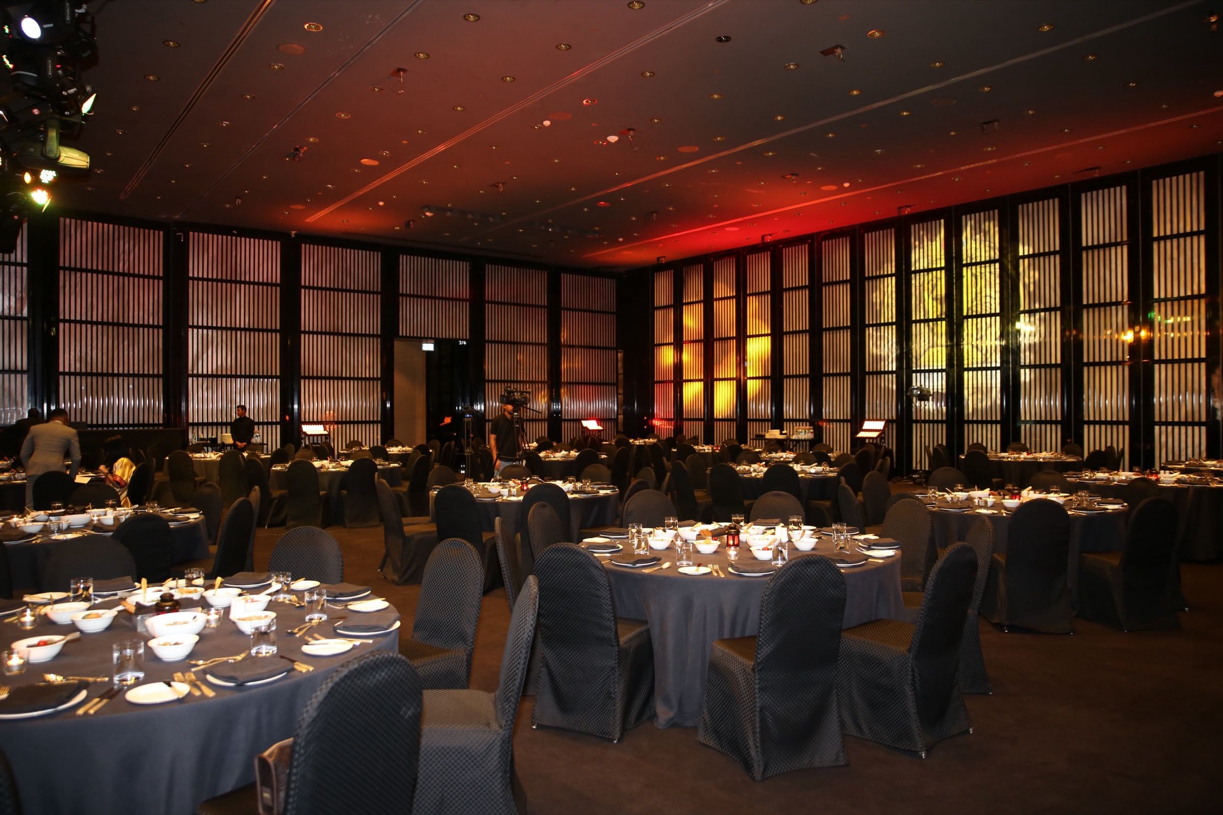 An elegantly decorated venue for a corporate gala dinner, featuring ambient lighting, floral centerpieces, and a grand chandelier