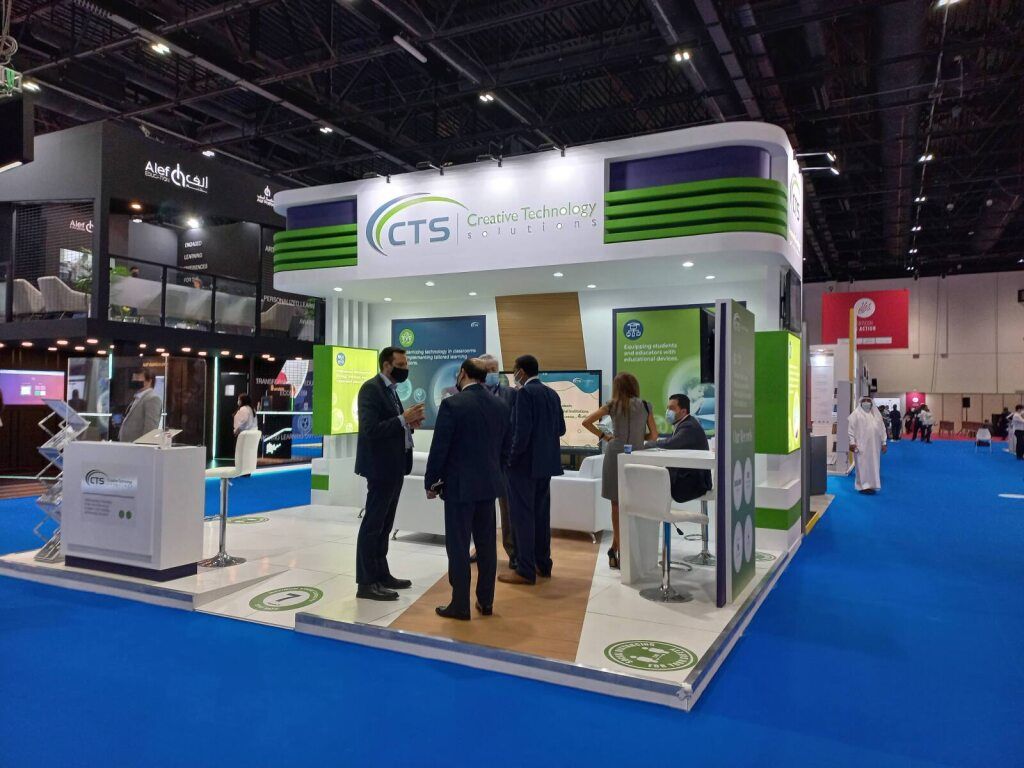 Green and white exhibition stand with visitors at a trade fair