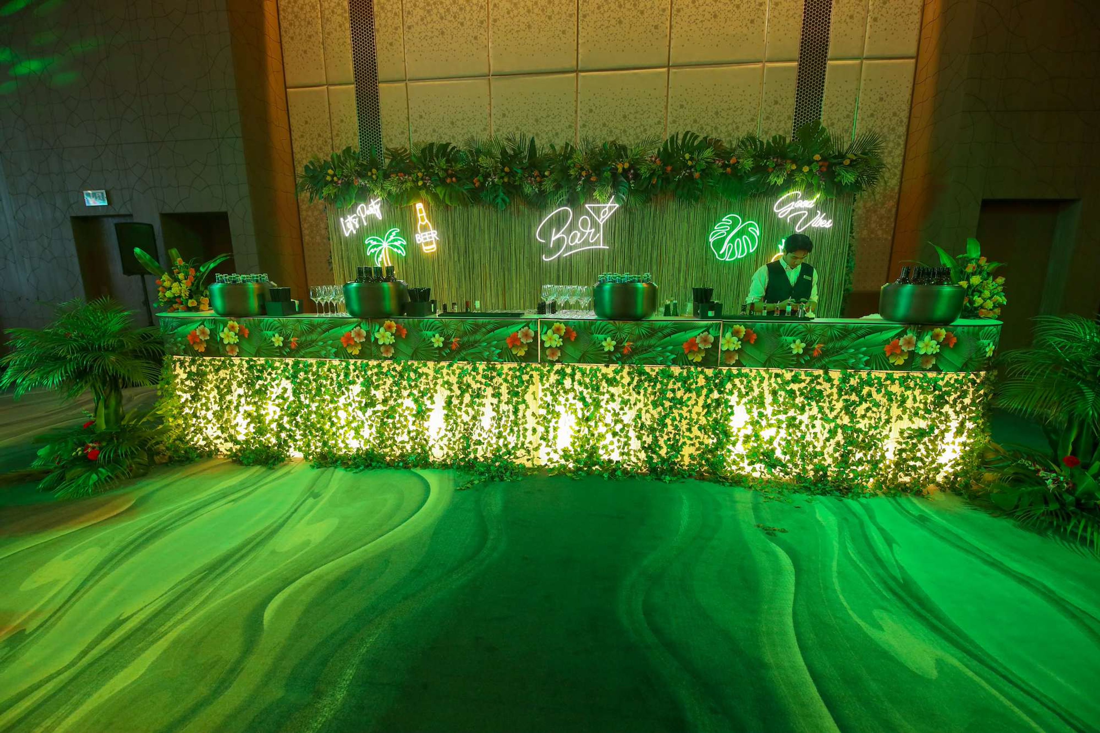 Themed reception bar with tropical greenery and neon signs at a corporate gala dinner