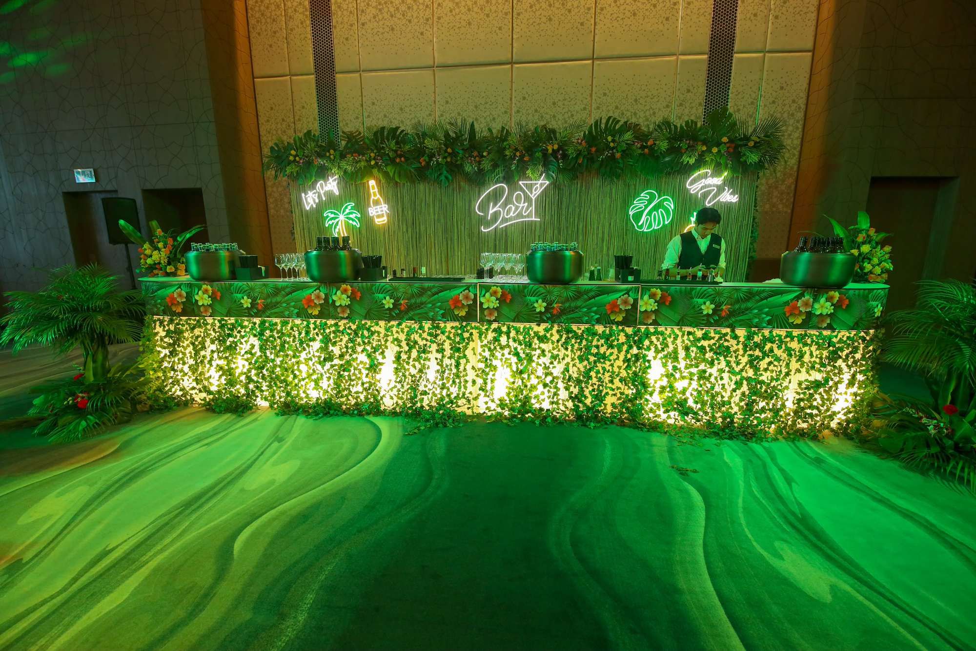 Themed reception bar with tropical greenery and neon signs at a corporate gala dinner