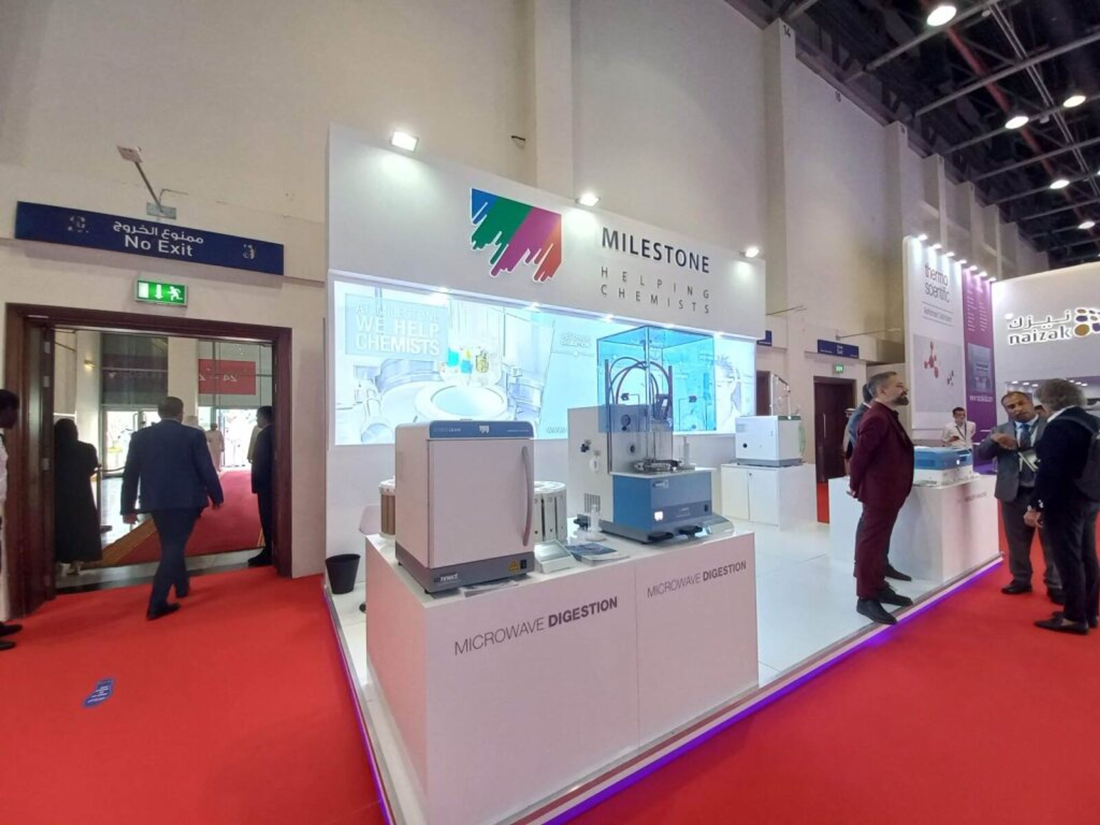 Exhibition stand with a white counter and visitors in conversation