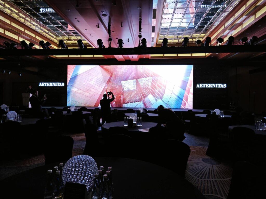 Guests at a luxury brand event with a large screen display
