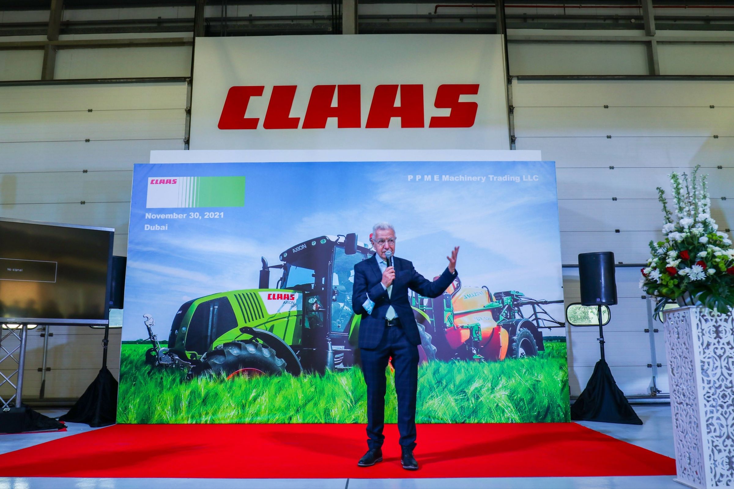Presenter on stage in front of a large agricultural brand backdrop