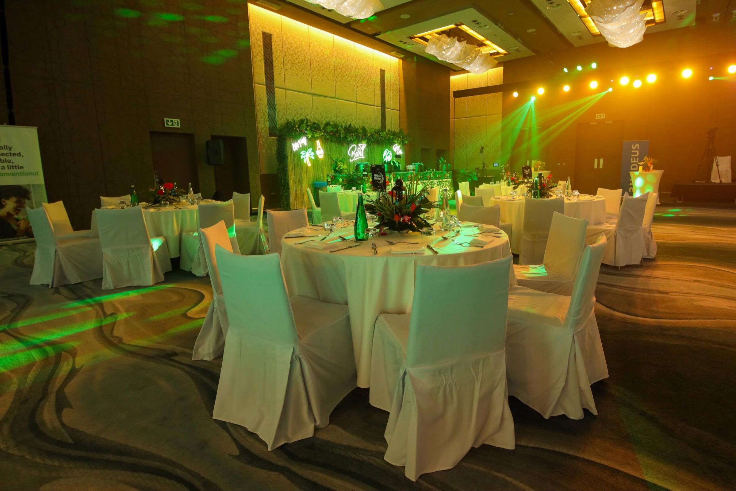Dinner tables with white chair covers under green lighting