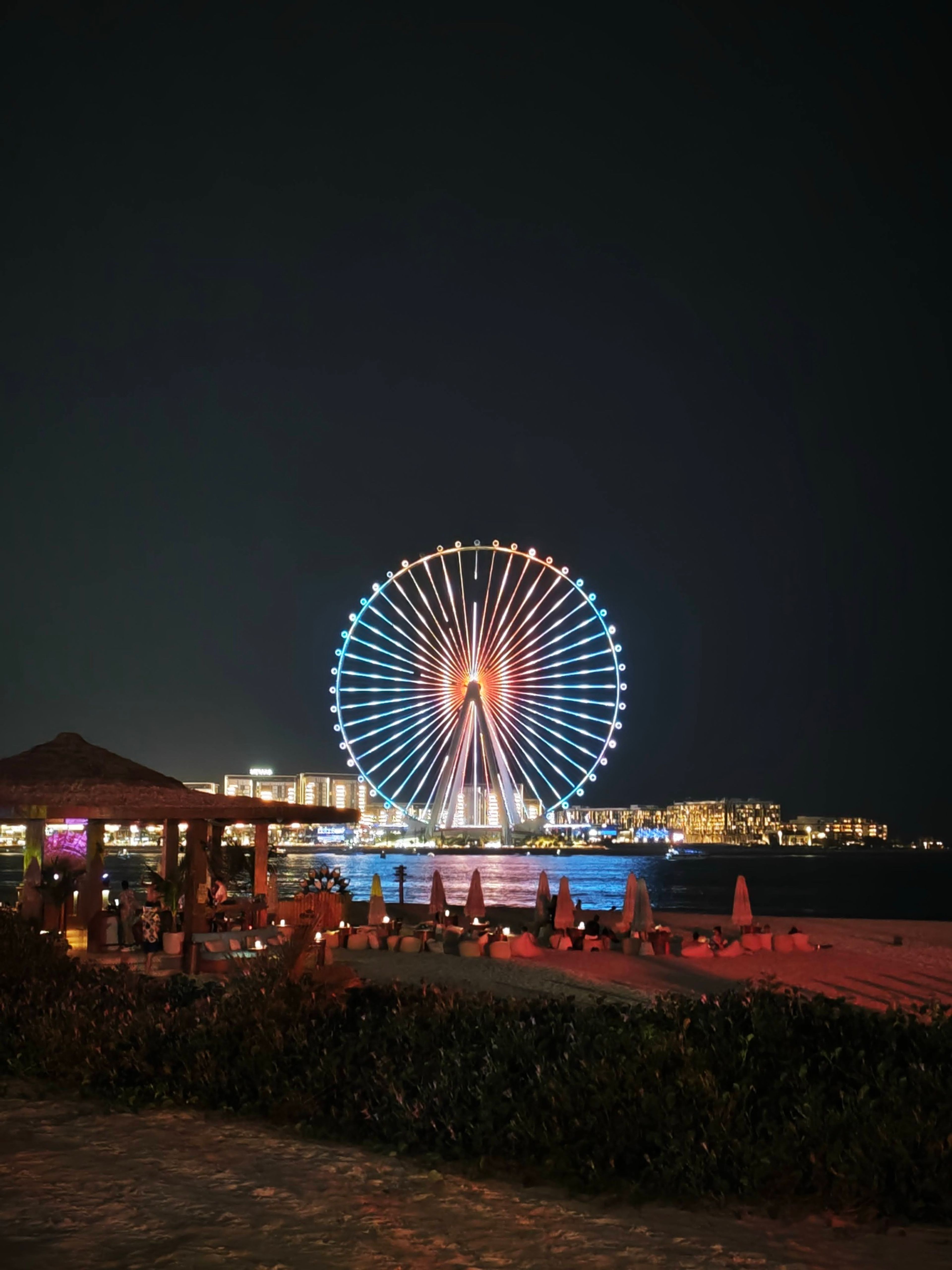 Ain Dubai observation wheel lit up at night beside an event venue