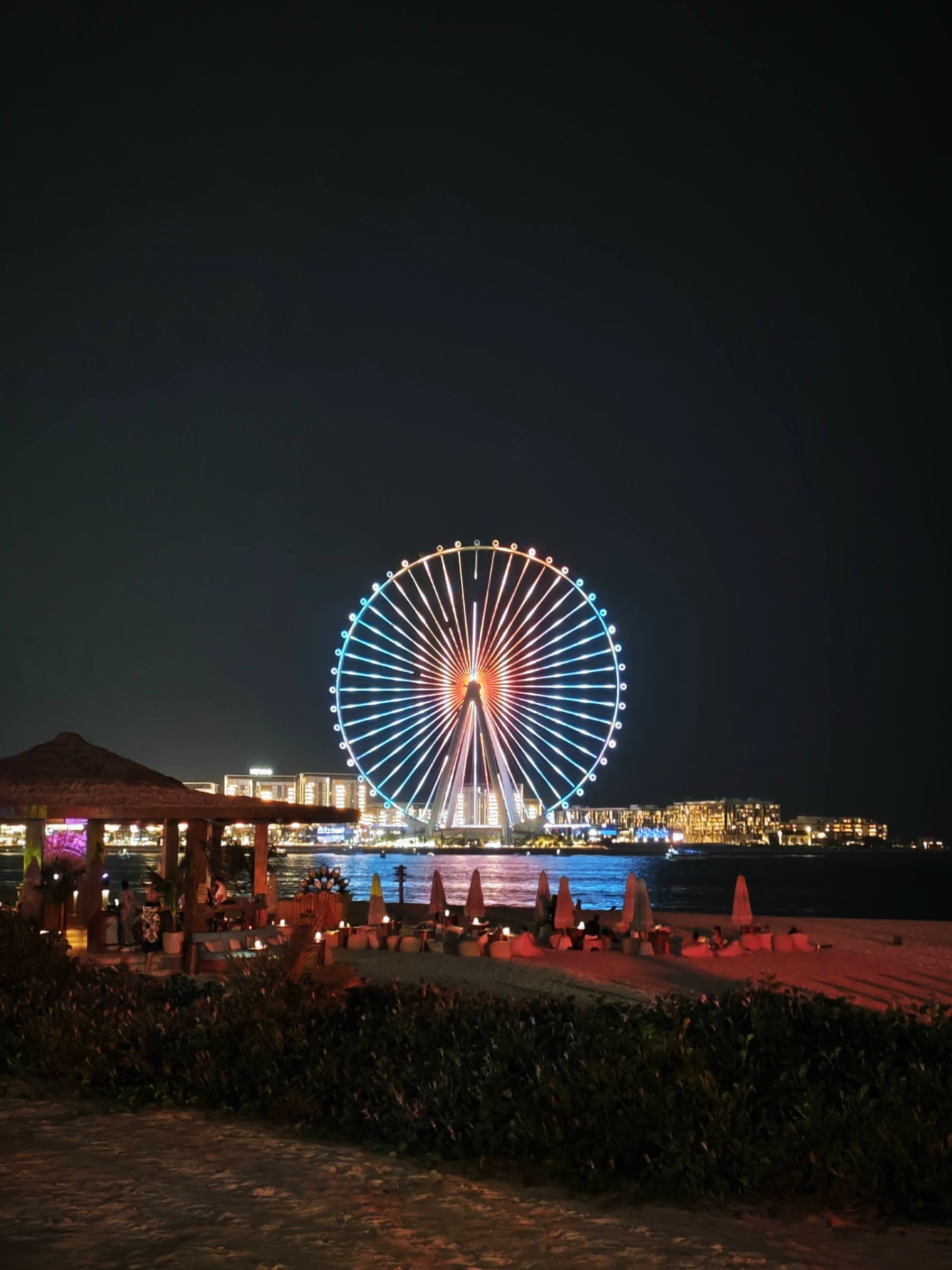 Ain Dubai observation wheel lit up at night beside an event venue