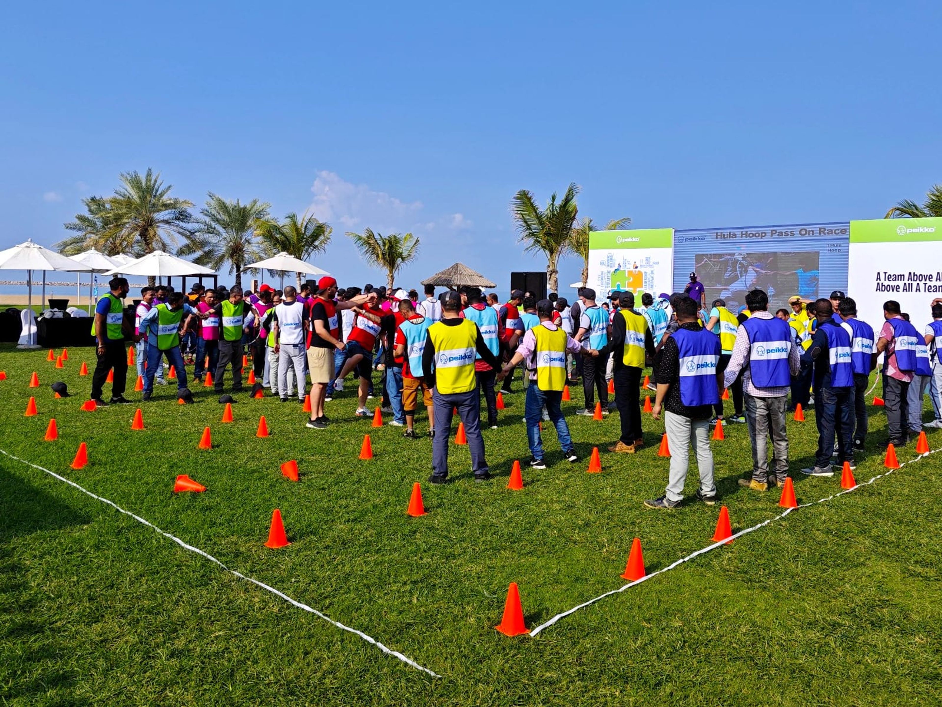 Staff lined up in team vests on the lawn for the Peikko Gulf team building day at Hilton Ras Al Khaimah