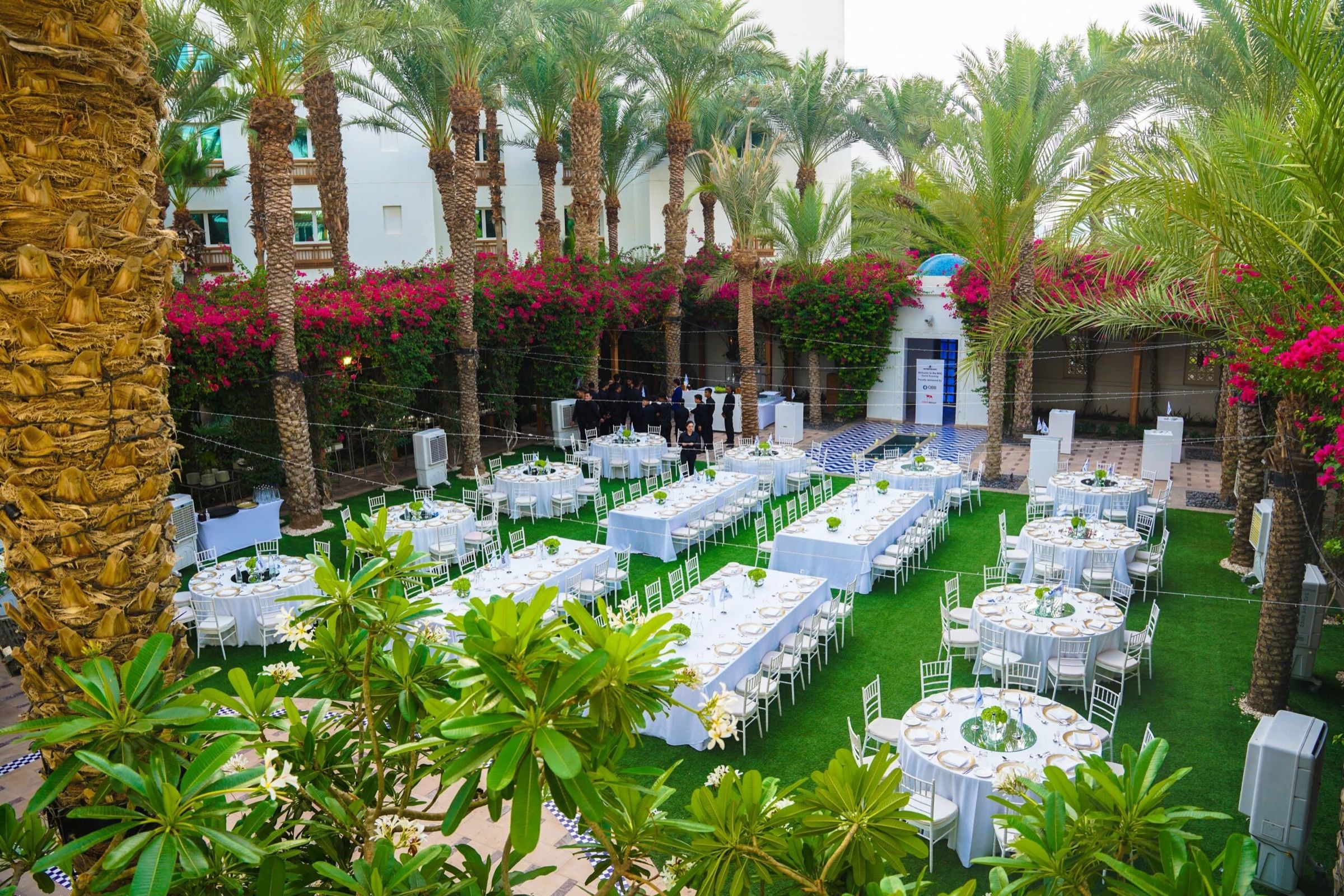 Outdoor garden dinner with long tables set among palm trees
