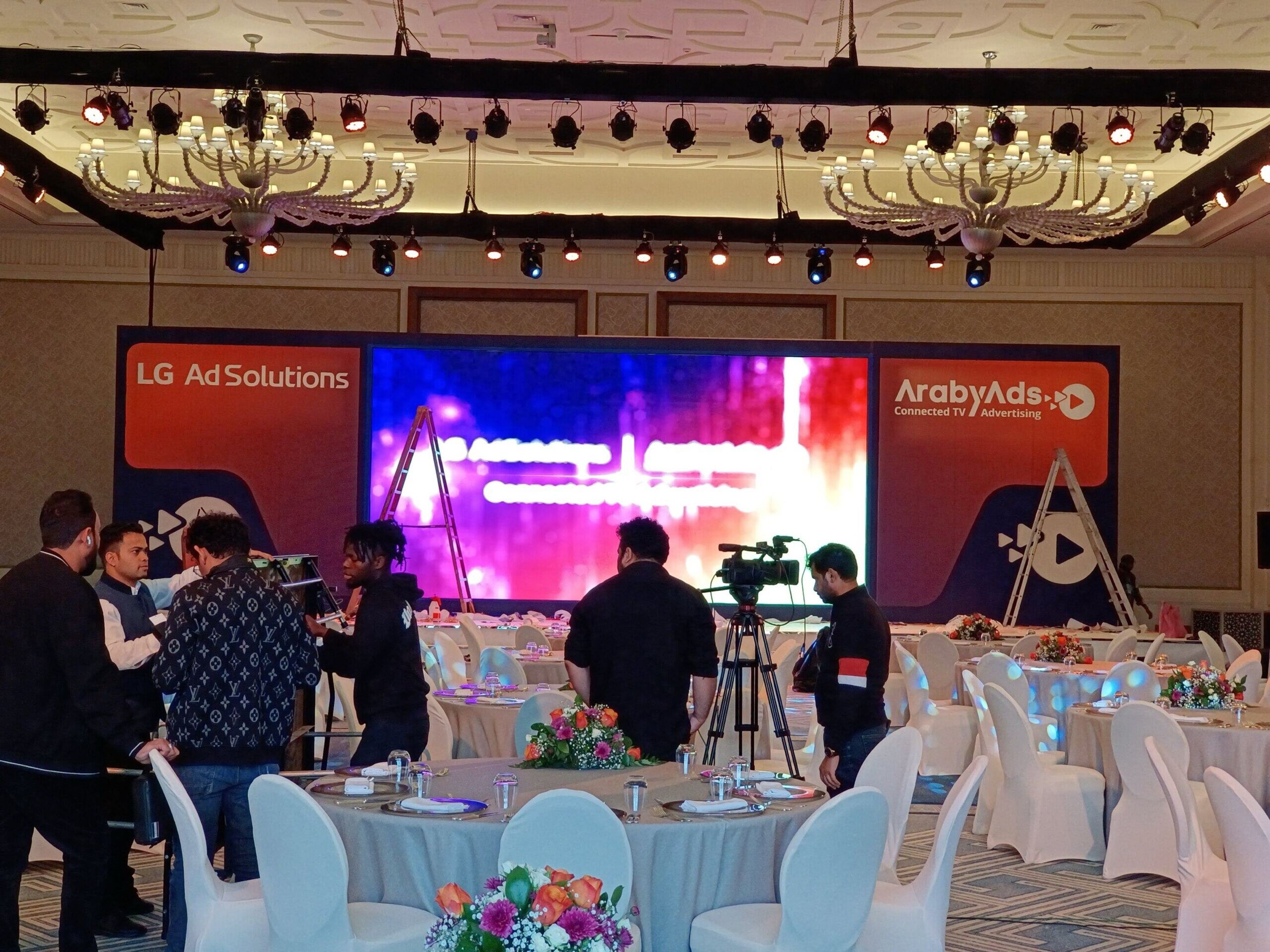 Camera crew filming a corporate event with a large LED stage screen
