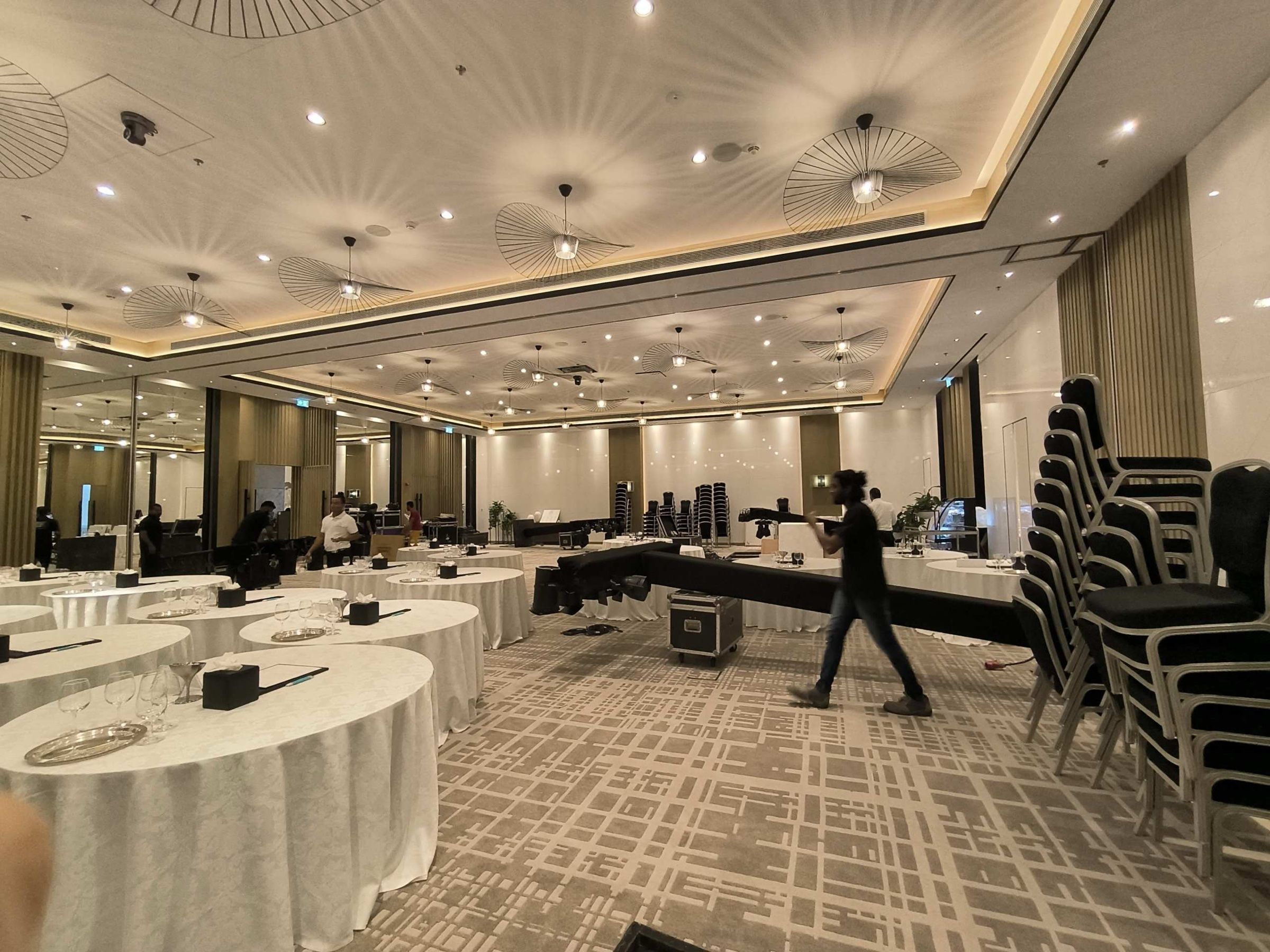 Banquet hall being set up with round tables and chairs before an event