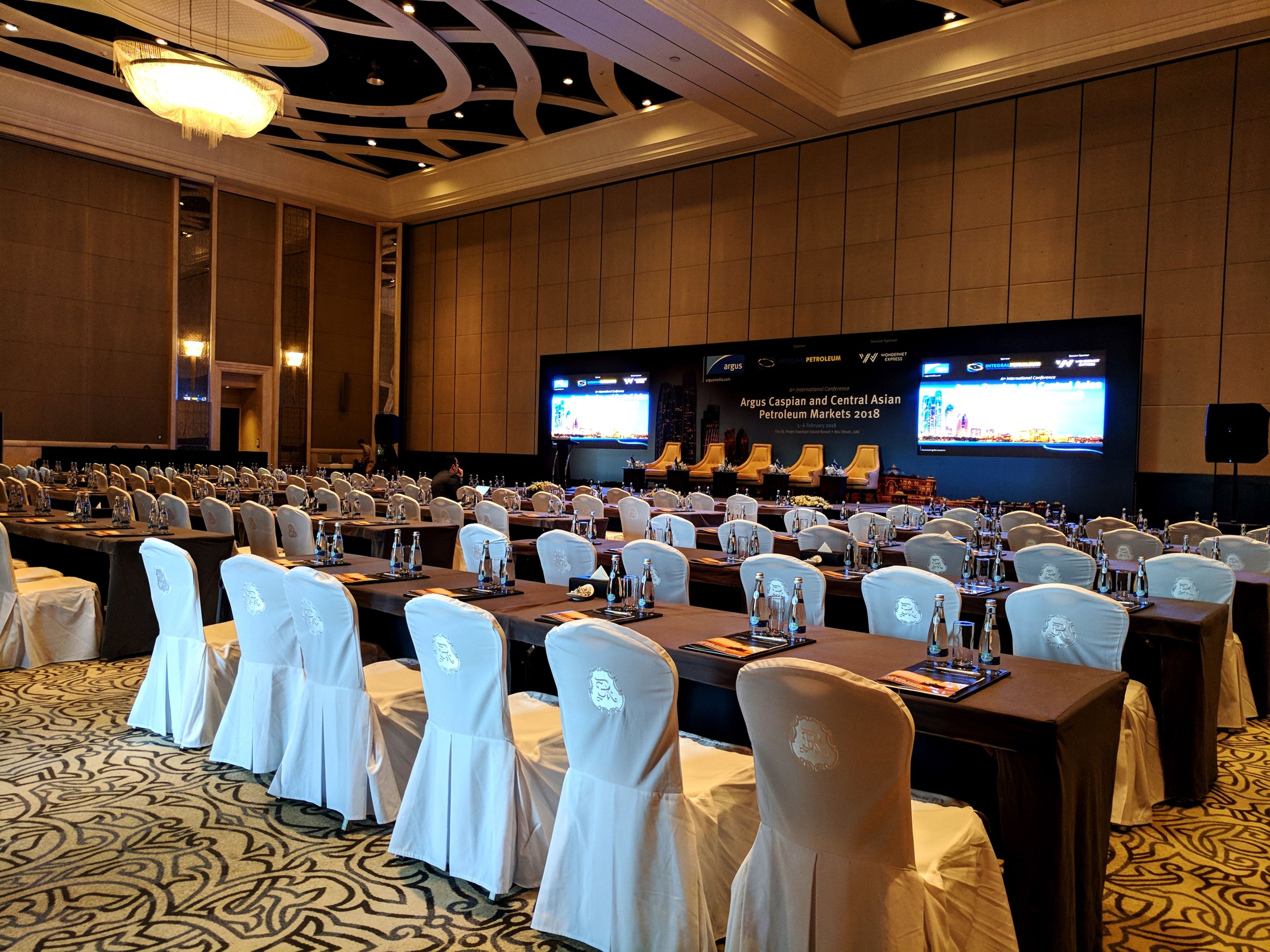 Ballroom set in classroom layout for an industry conference, with LED screens either side of a panel stage