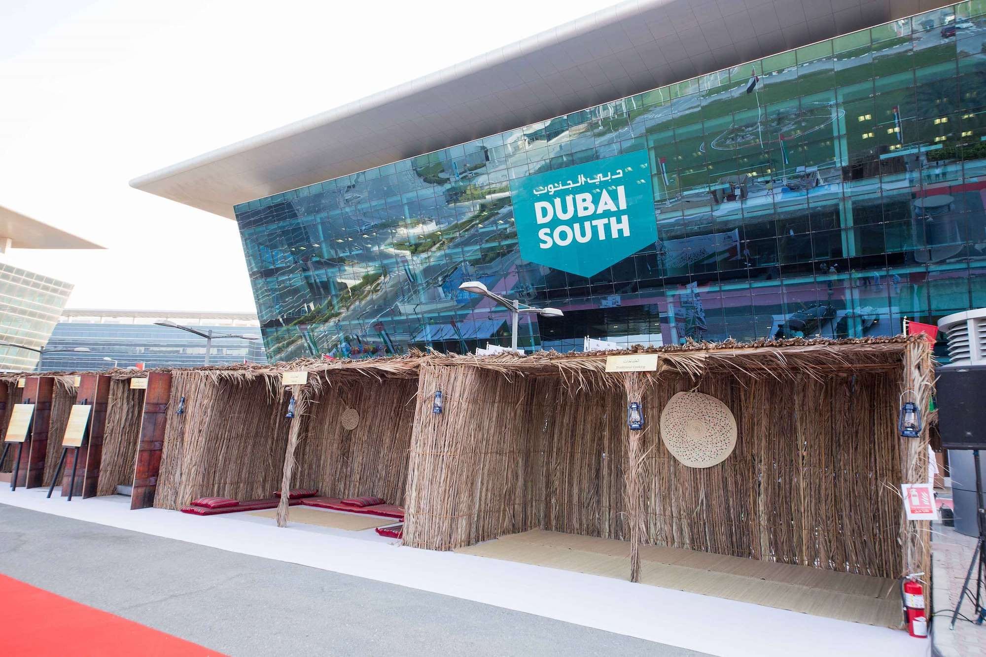 Row of palm frond souq stalls in front of the Dubai South headquarters building